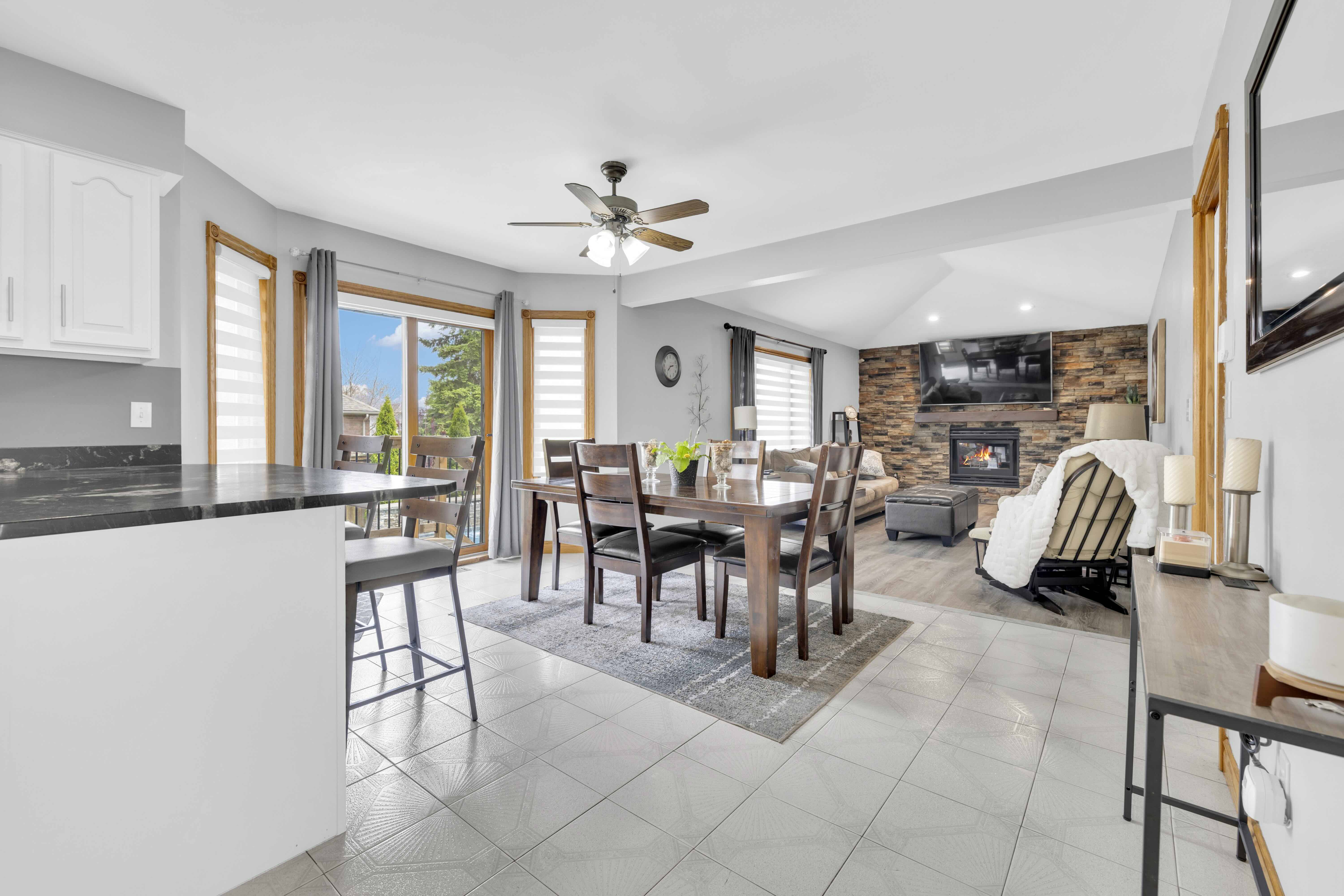 Open concept dining and living room with stone fireplace and large windows