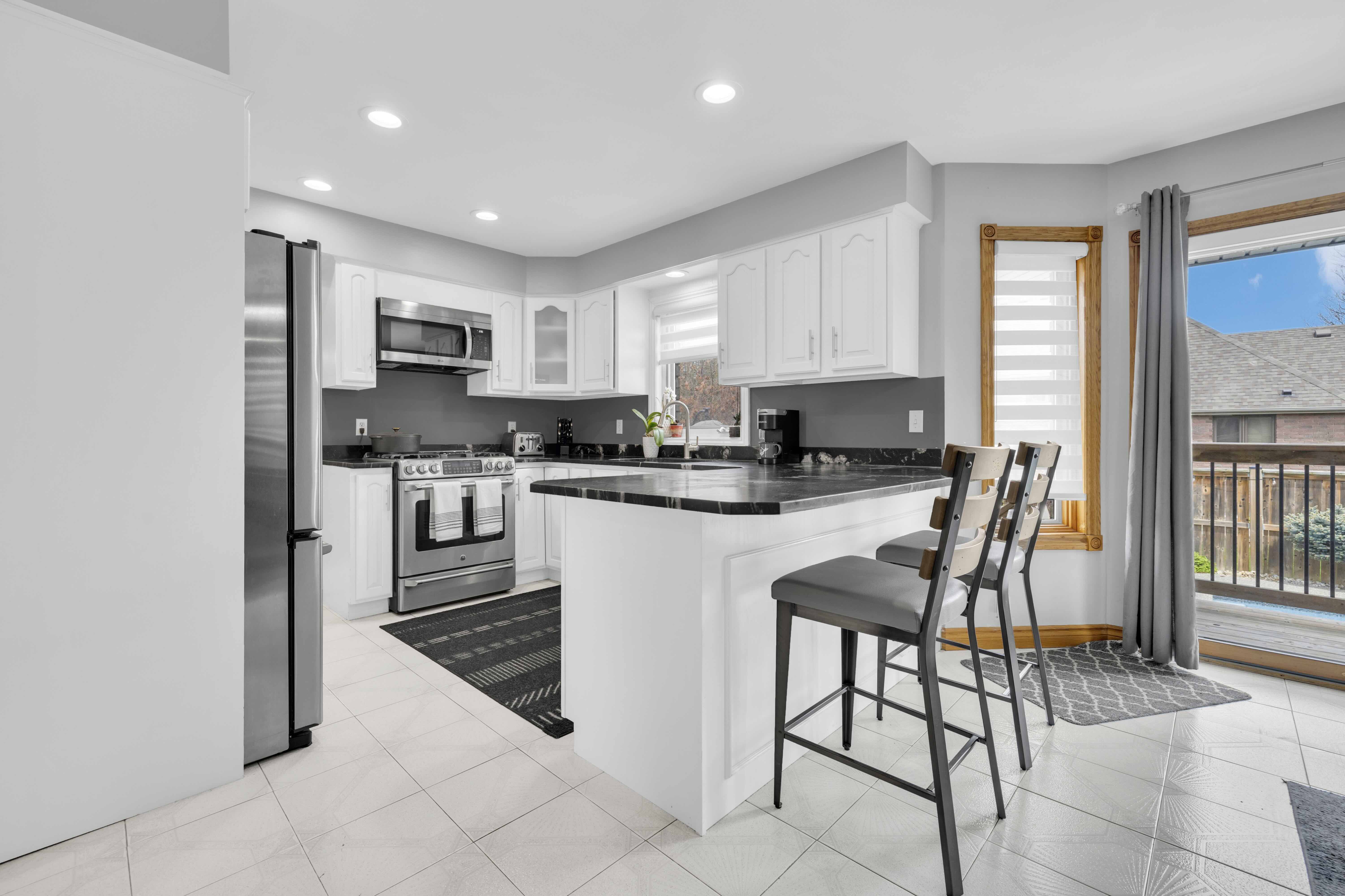 Kitchen island with bar stools, white cabinets and black granite