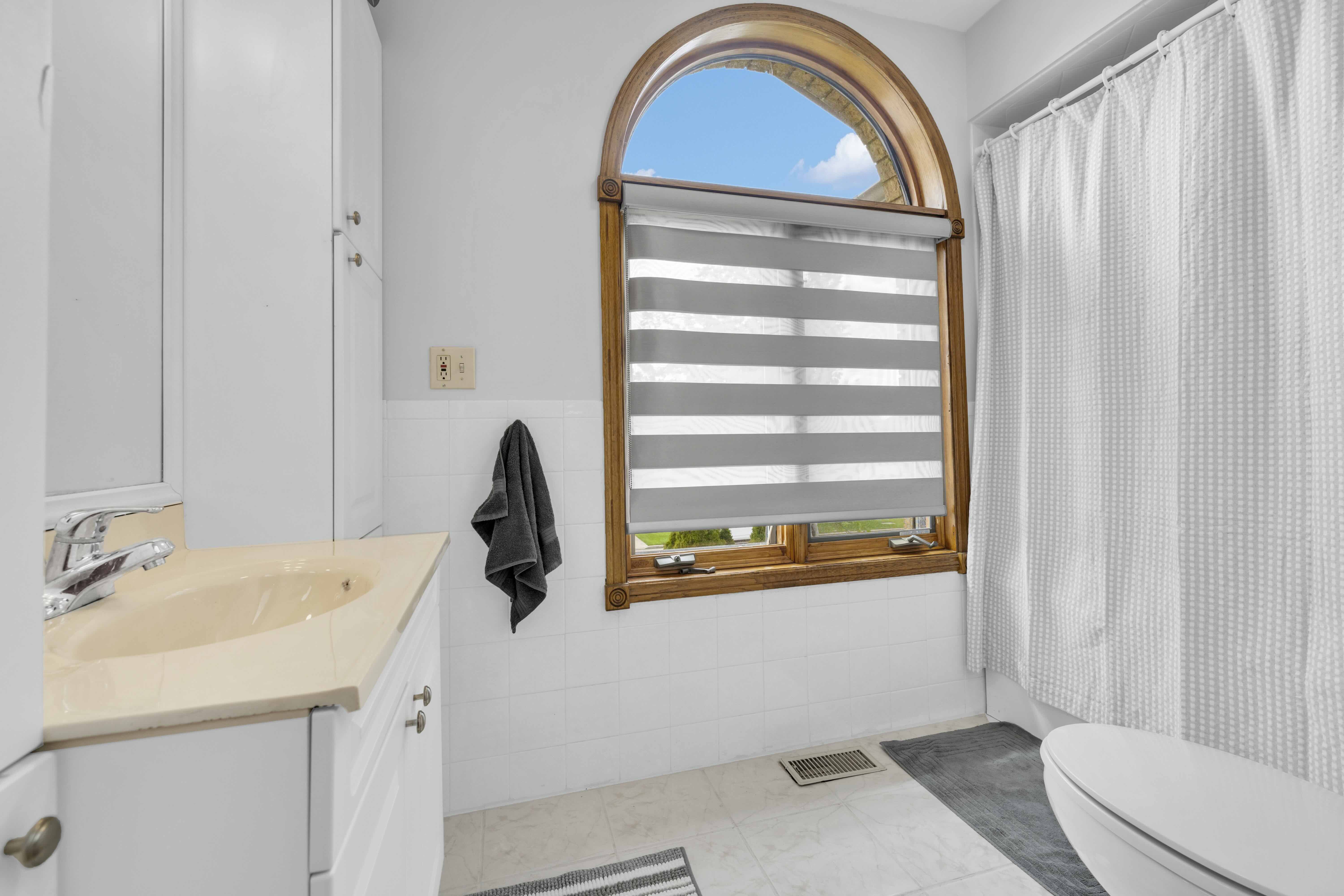 Bathroom with arched window and white vanity