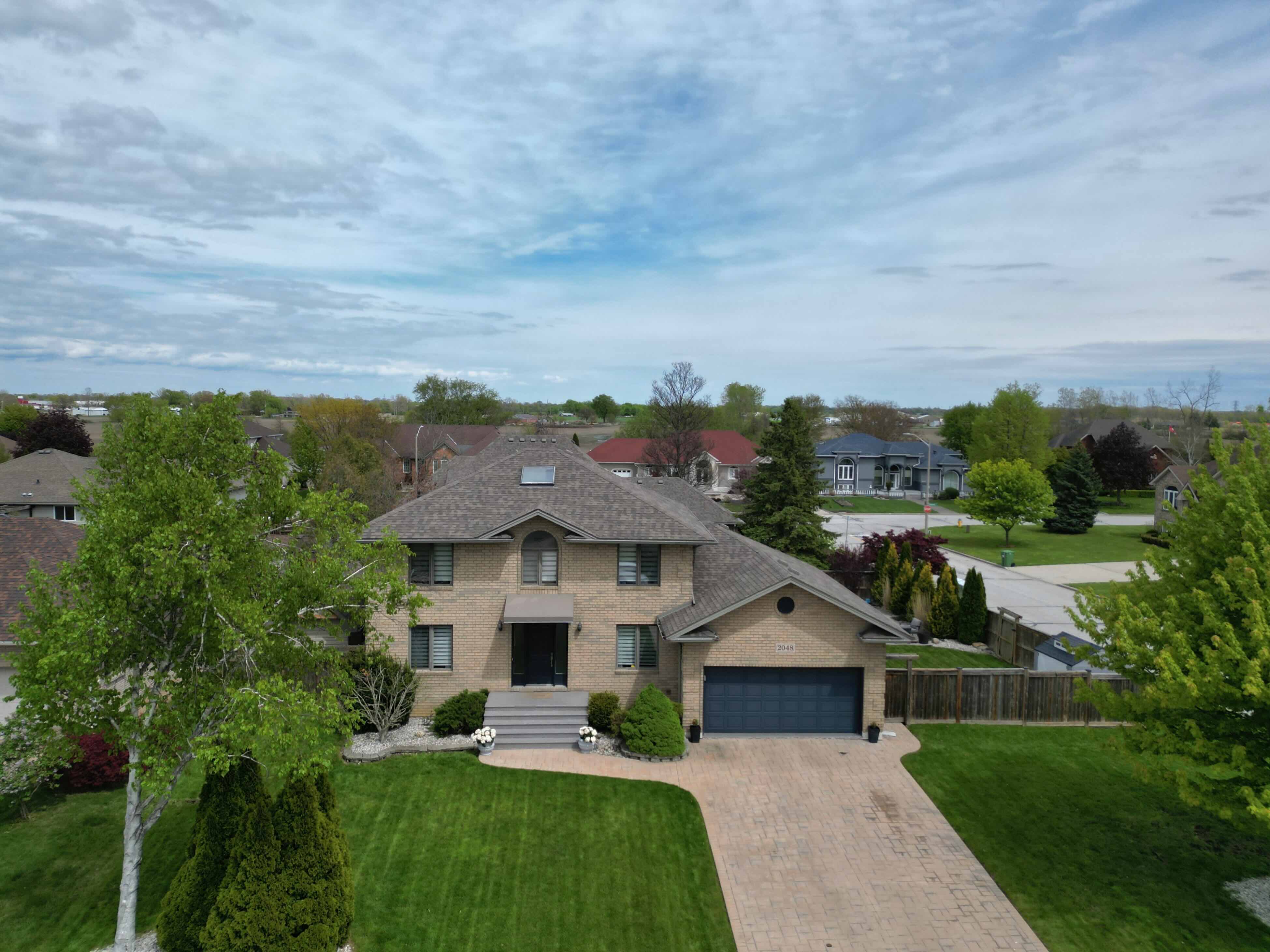 Aerial view of corner lot home with green surroundings
