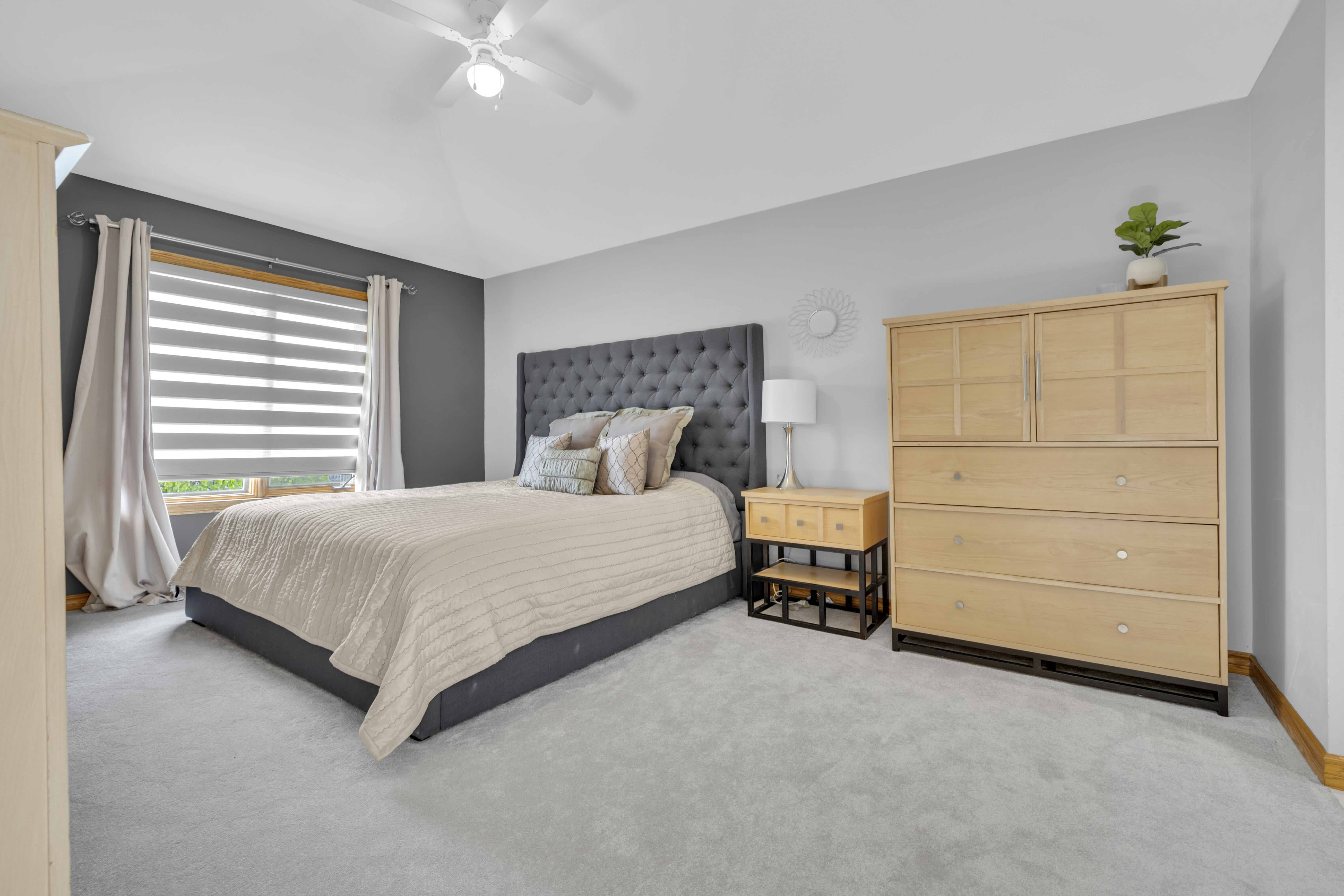 Primary bedroom with tufted headboard and grey accent wall