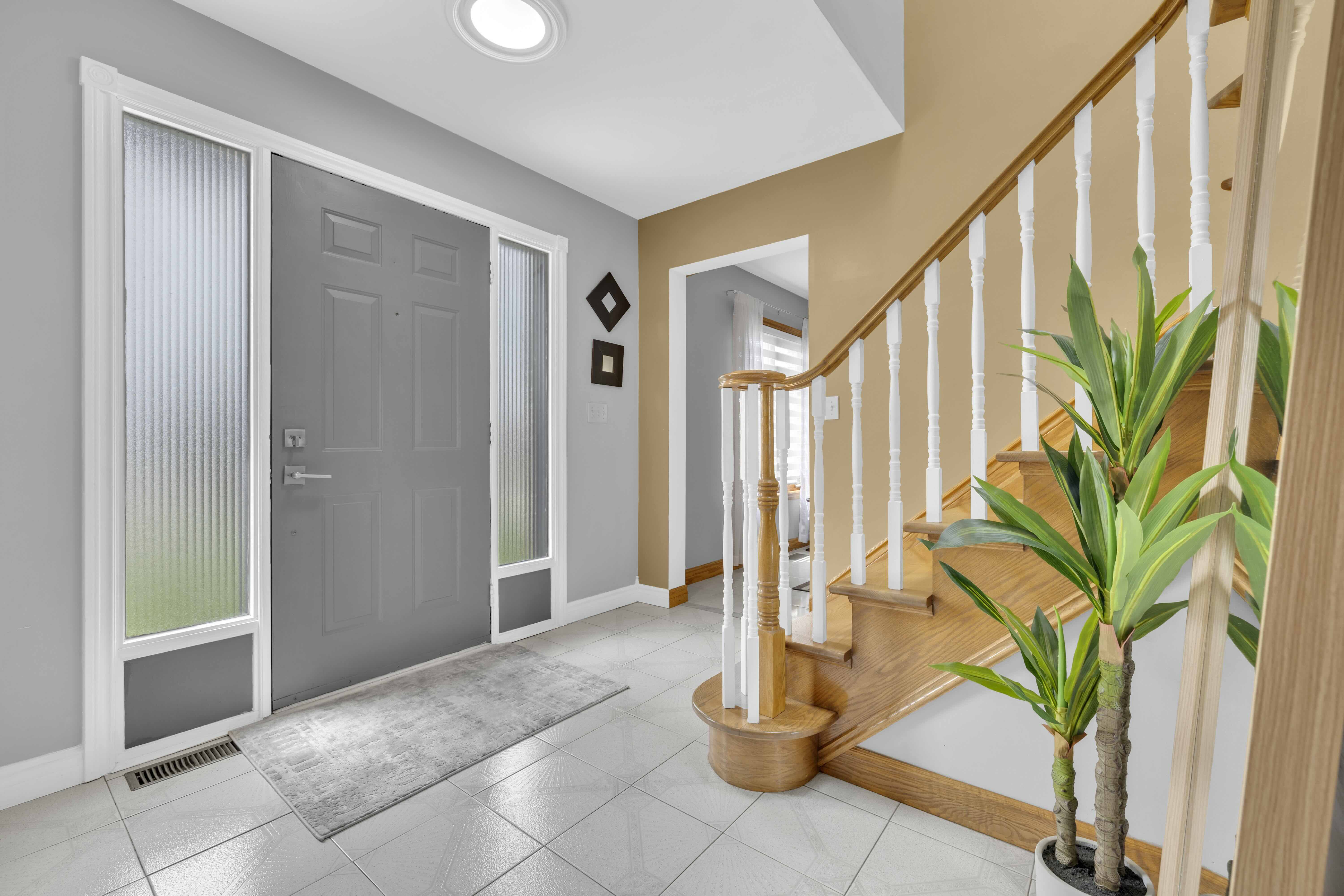 Bright foyer with skylight, tile floor and wooden staircase