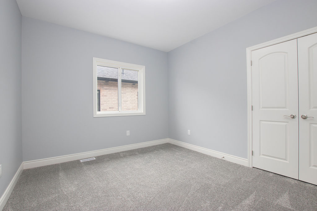 Carpeted bedroom with window and double white closet doors