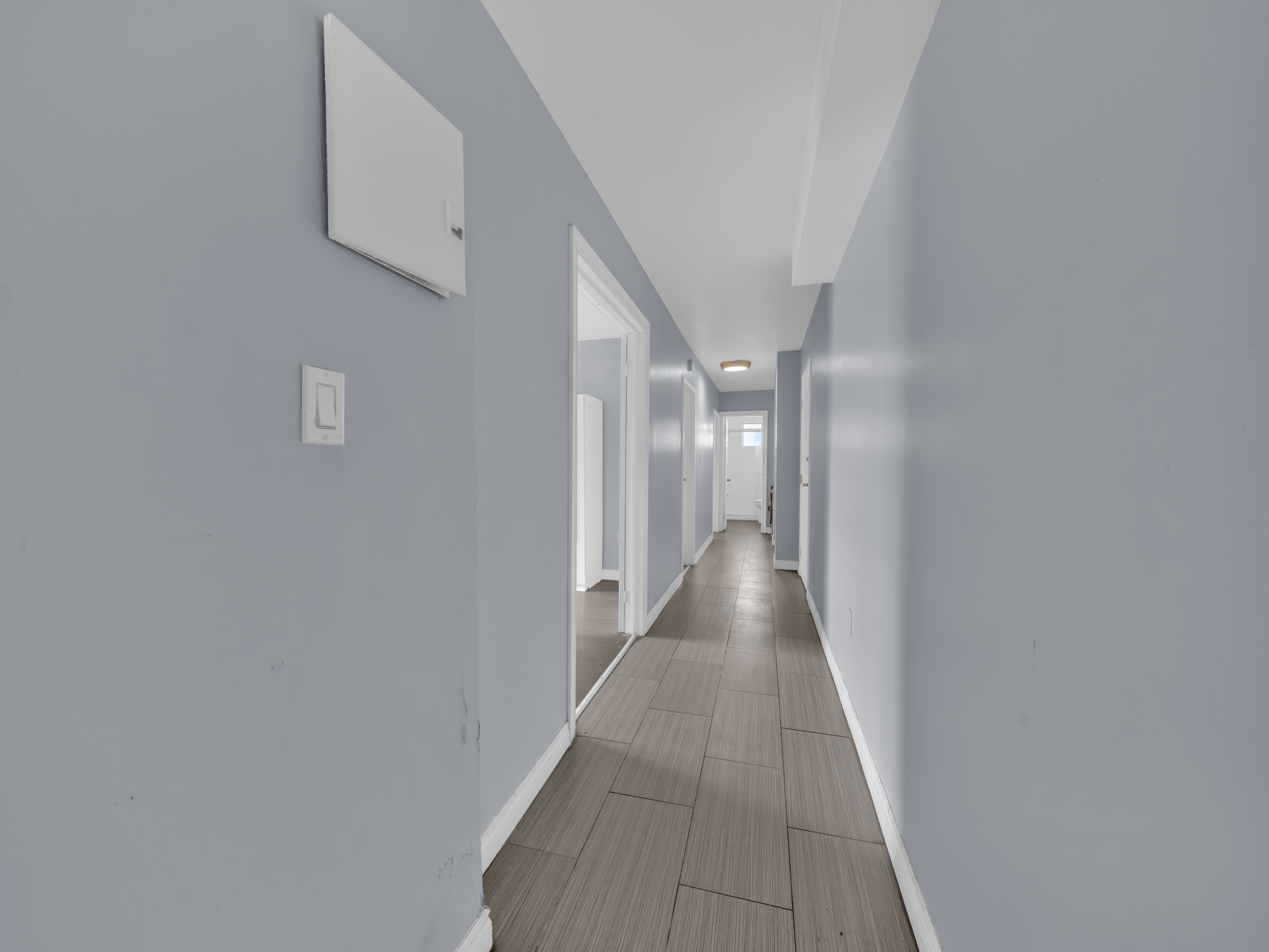 Long hallway with blue walls and tile floor