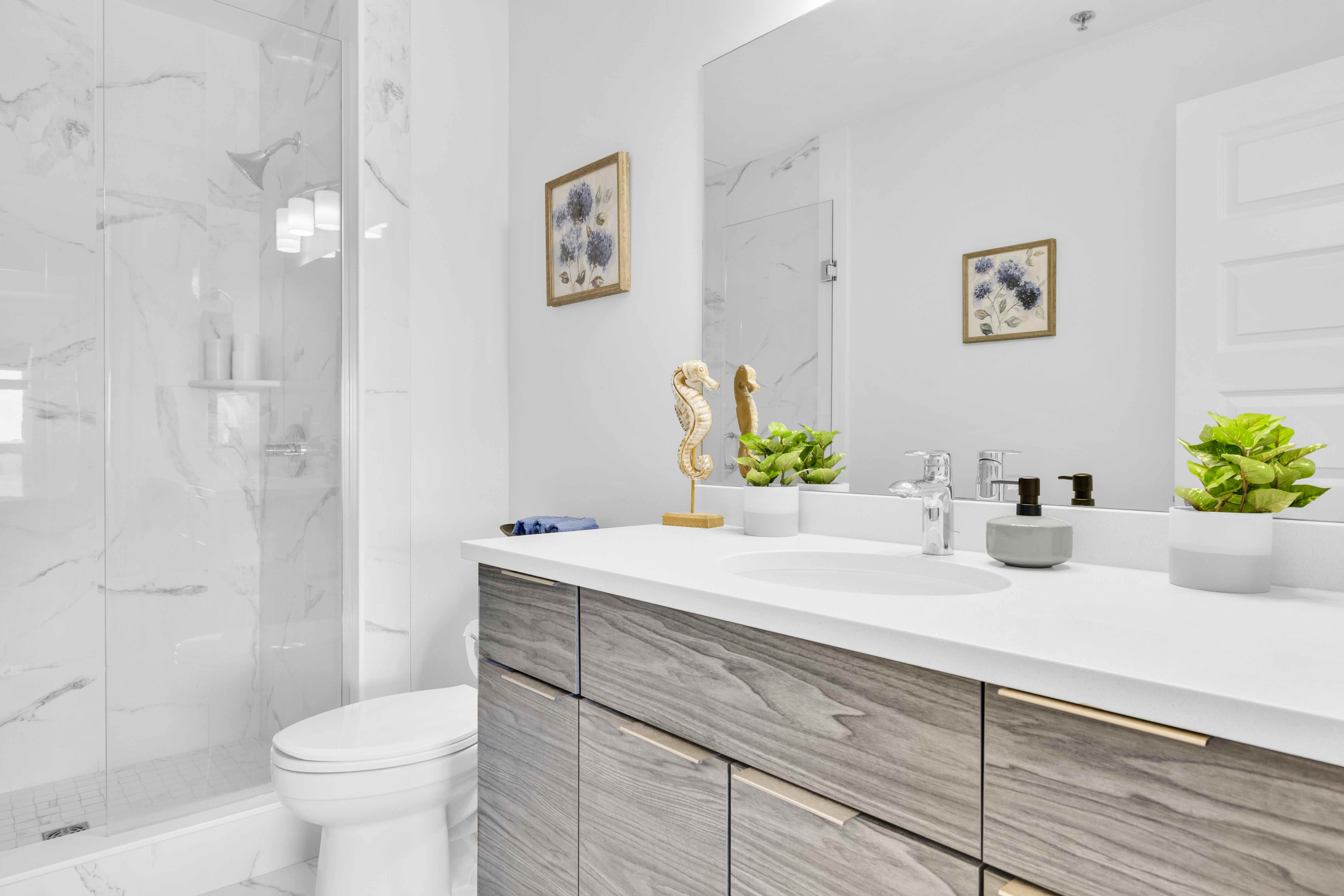 Bathroom with glass shower, wood-finish vanity, and mirror