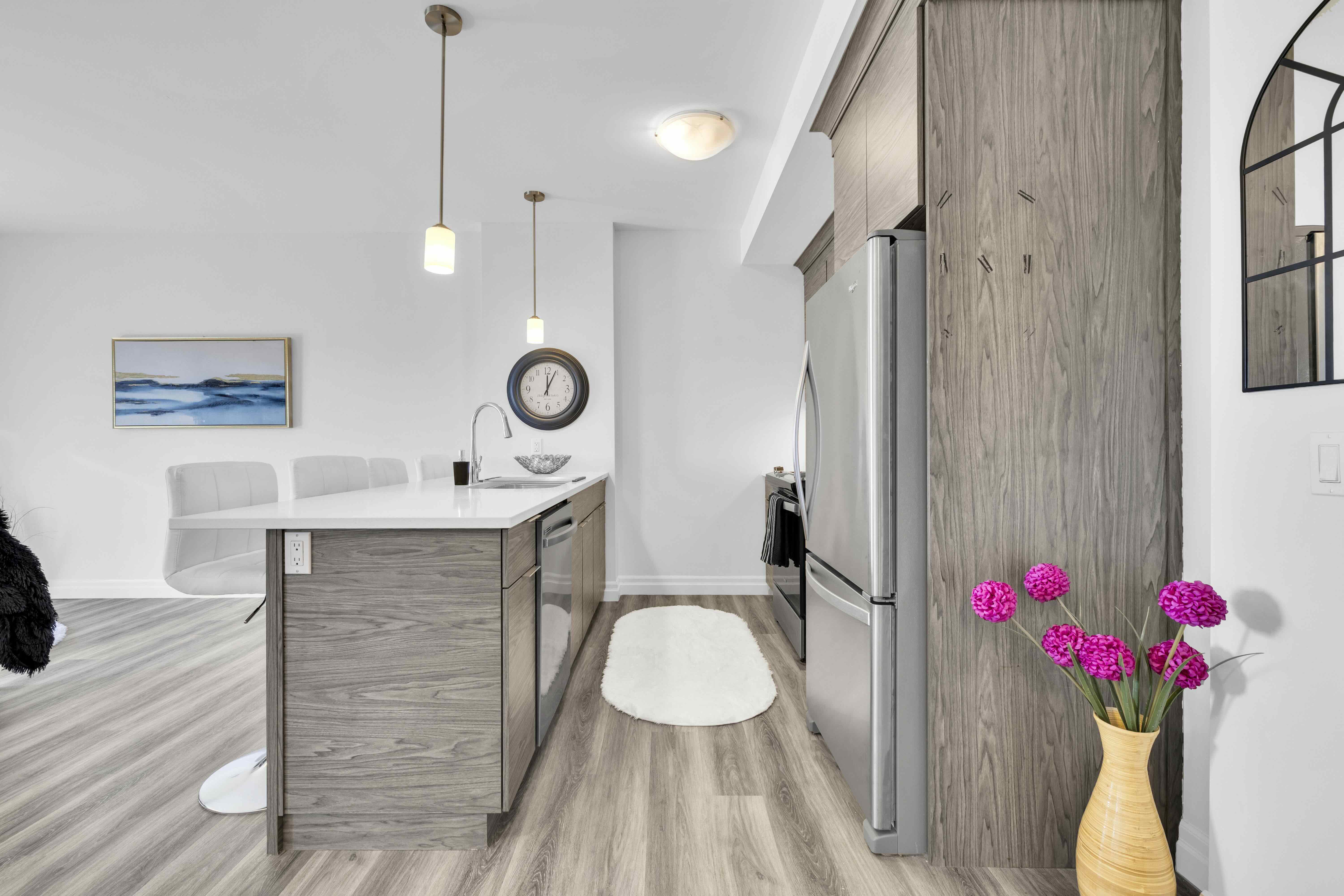 Kitchen island with bar stools, refrigerator, and artwork