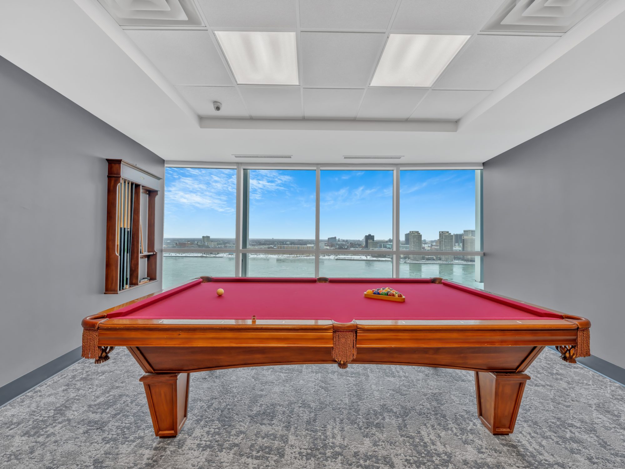 Pool table with floor-to-ceiling window and city water view