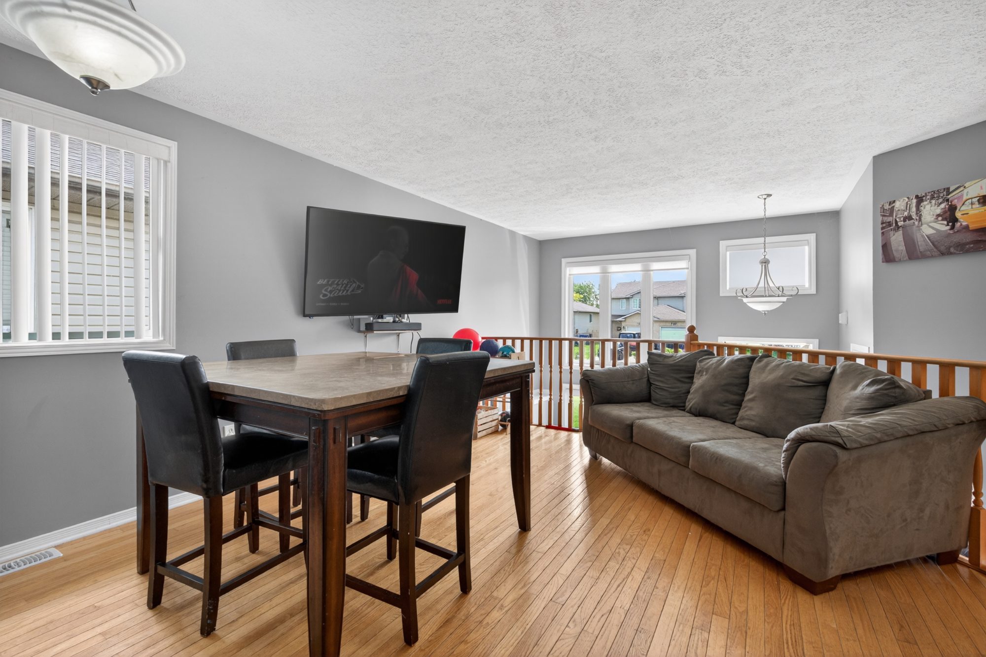 Living room with hardwood floors, large windows, and dining area