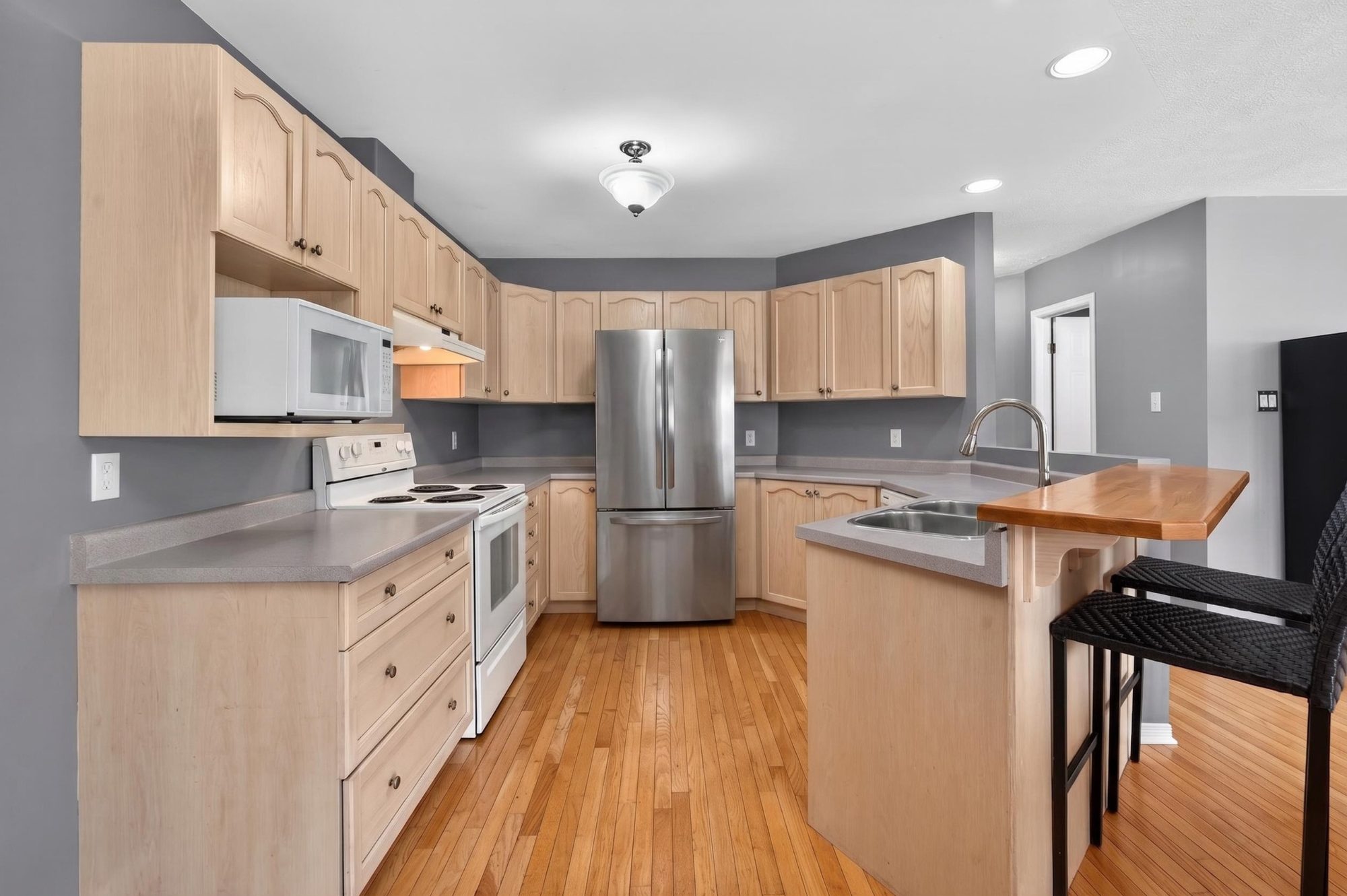 Kitchen with light maple cabinetry and stainless refrigerator
