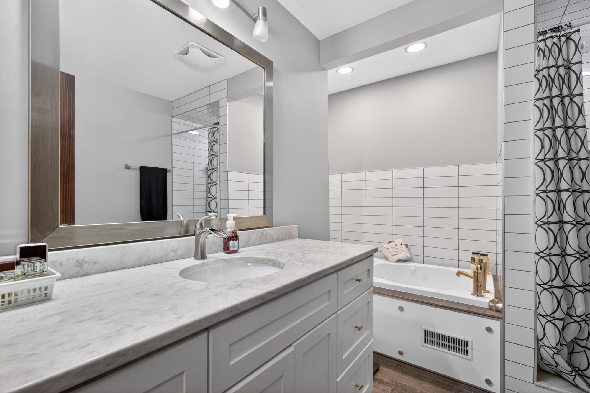 Bathroom - vanity with countertop, large mirror, bathtub with tile surround