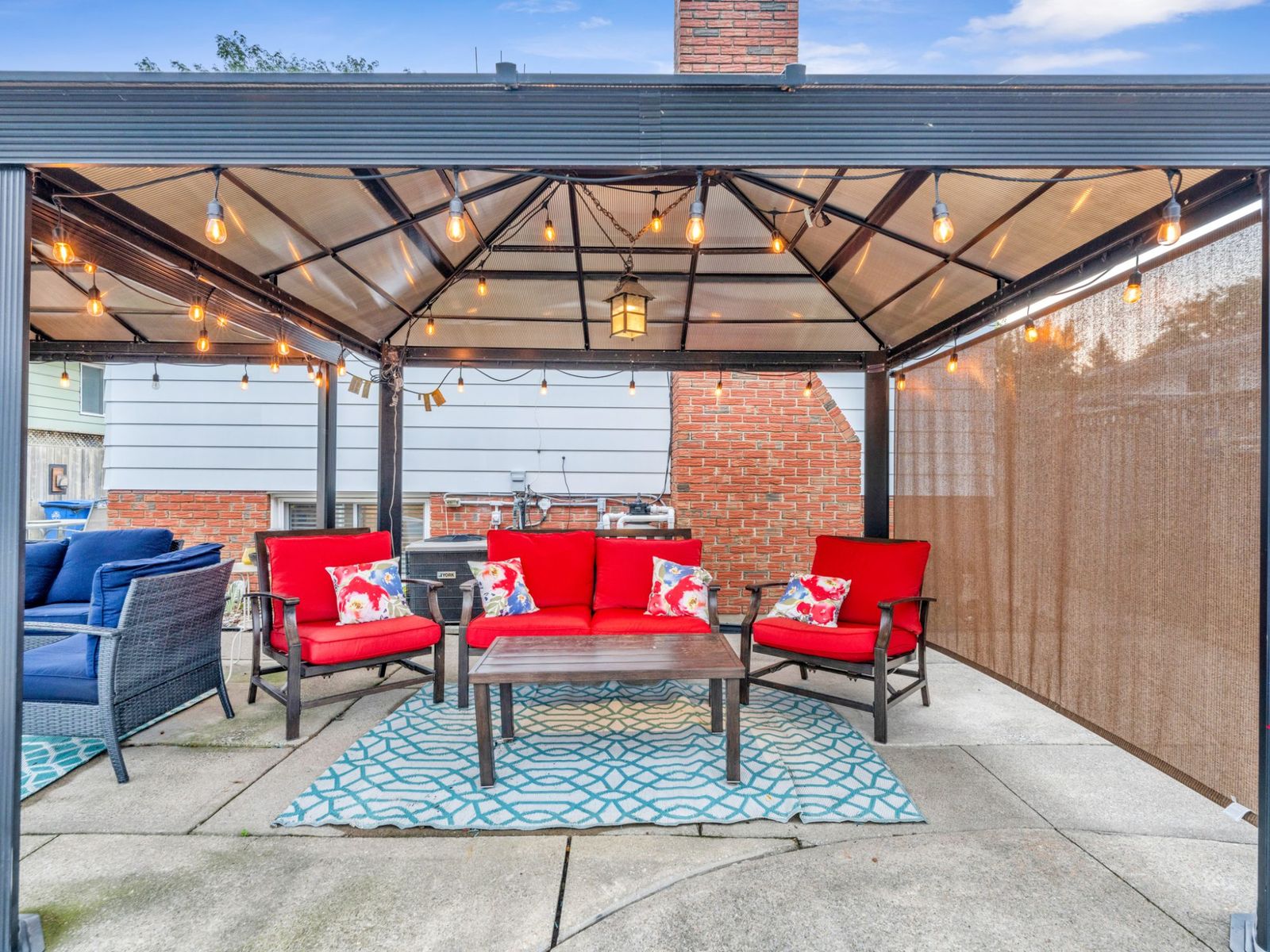Inside the gazebo: cushioned seating around a coffee table under string lights.