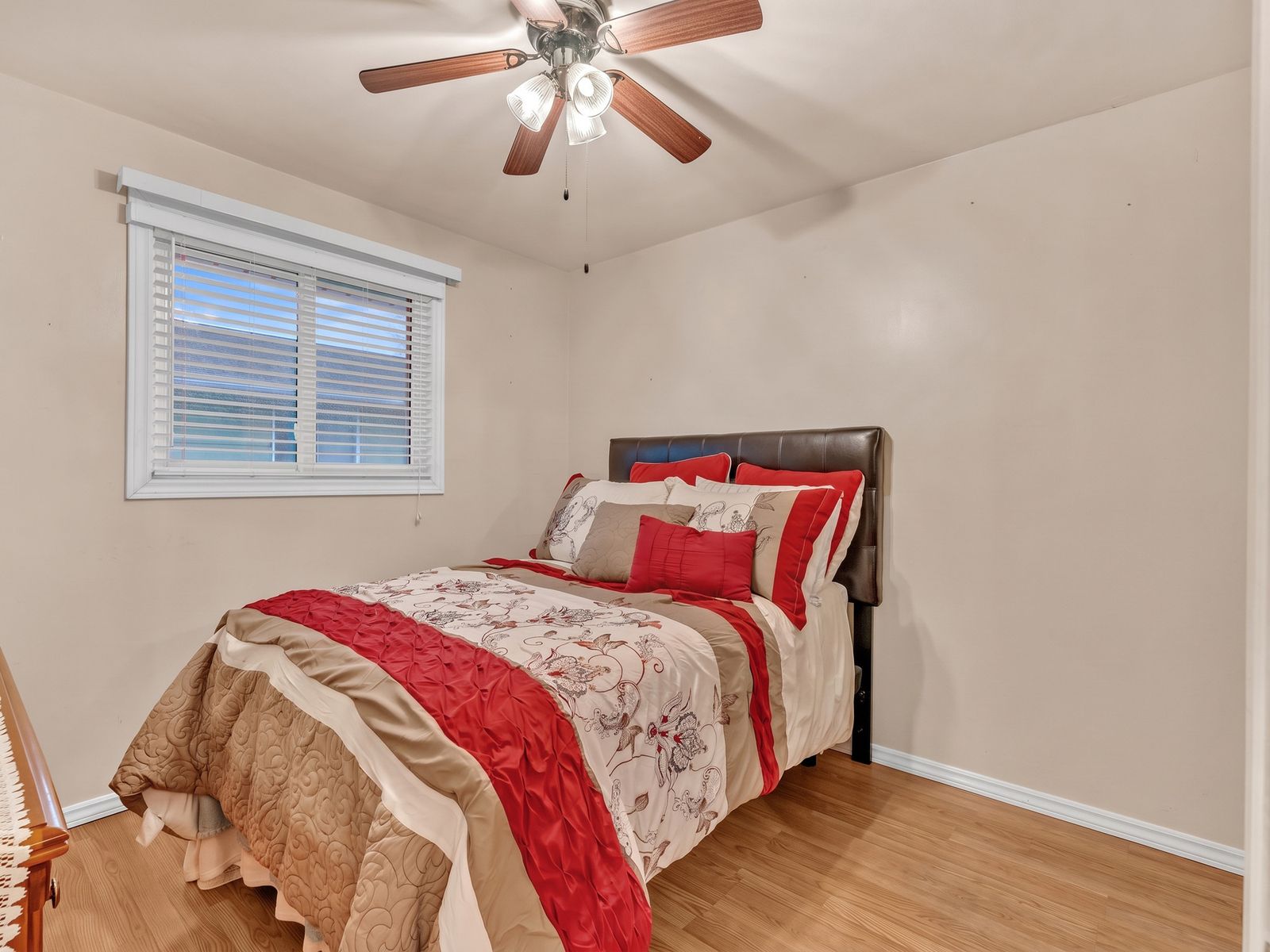The second bedroom with a bed, armchair and ceiling fan.