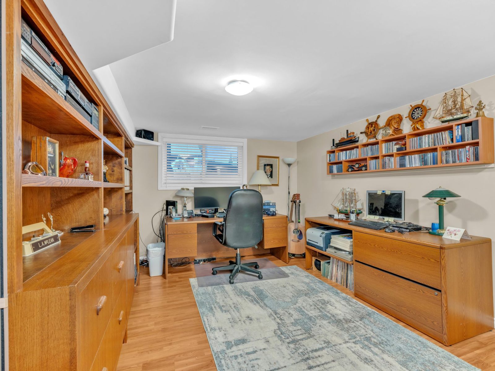 The office with built-in wood shelving, a desk and a window.