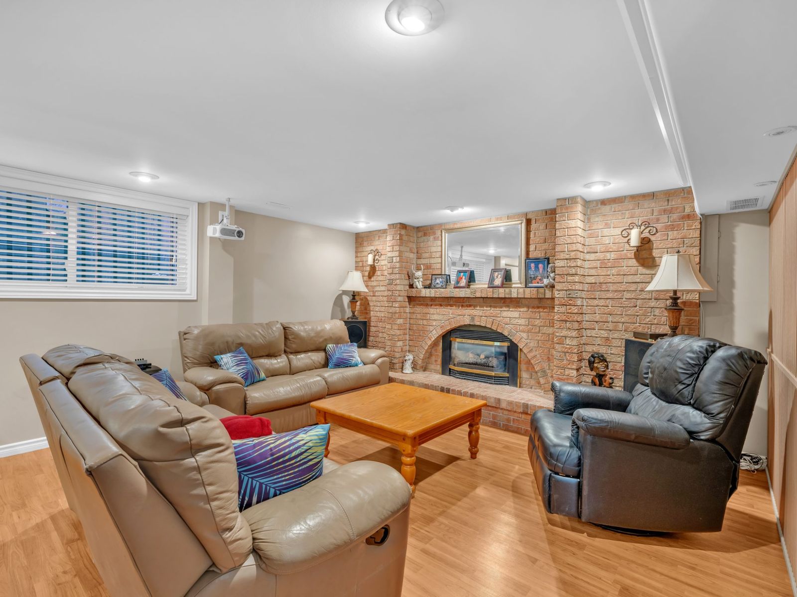 The family room with a brick fireplace, leather sofas and a ceiling projector.