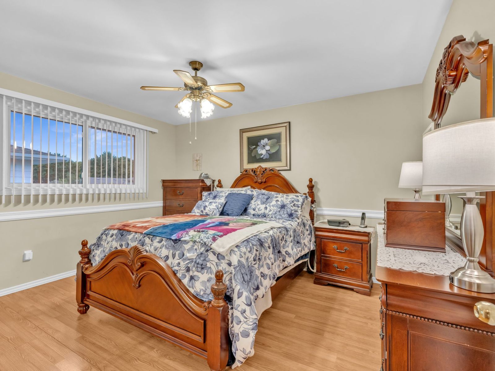 The primary bedroom with a wood bed frame, nightstands and ceiling fan.