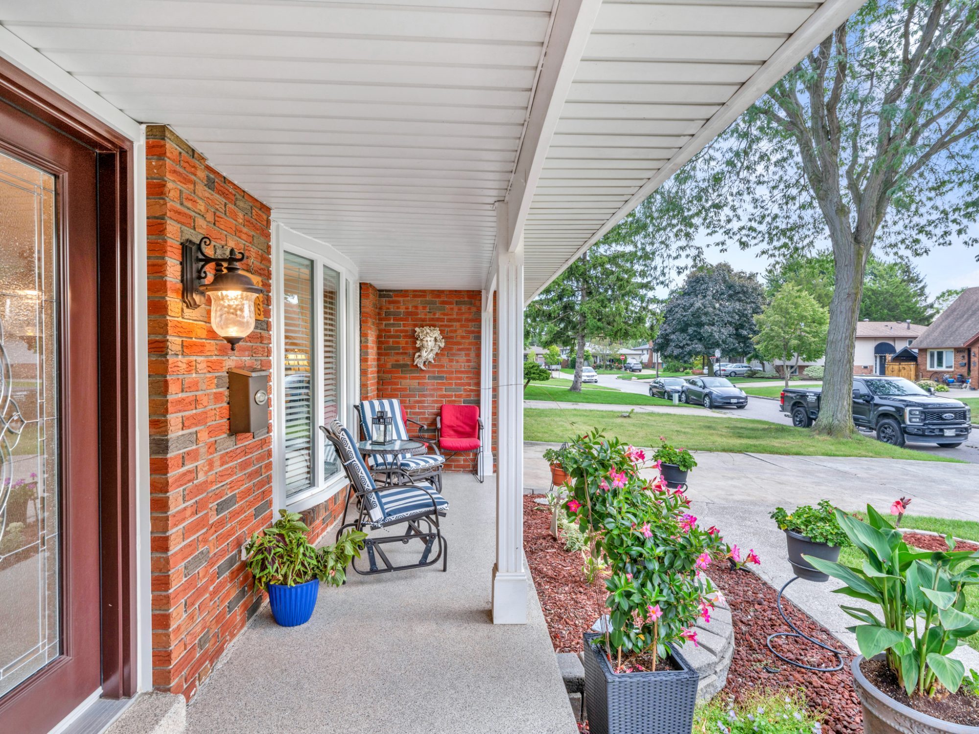 The covered front porch with chairs, plants and a view down the crescent.