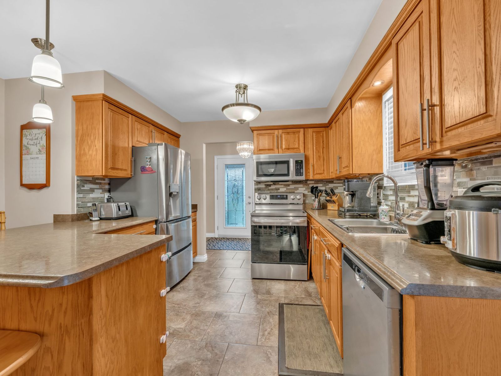 The kitchen: wood cabinets, stainless fridge and range, glass pendant lights.