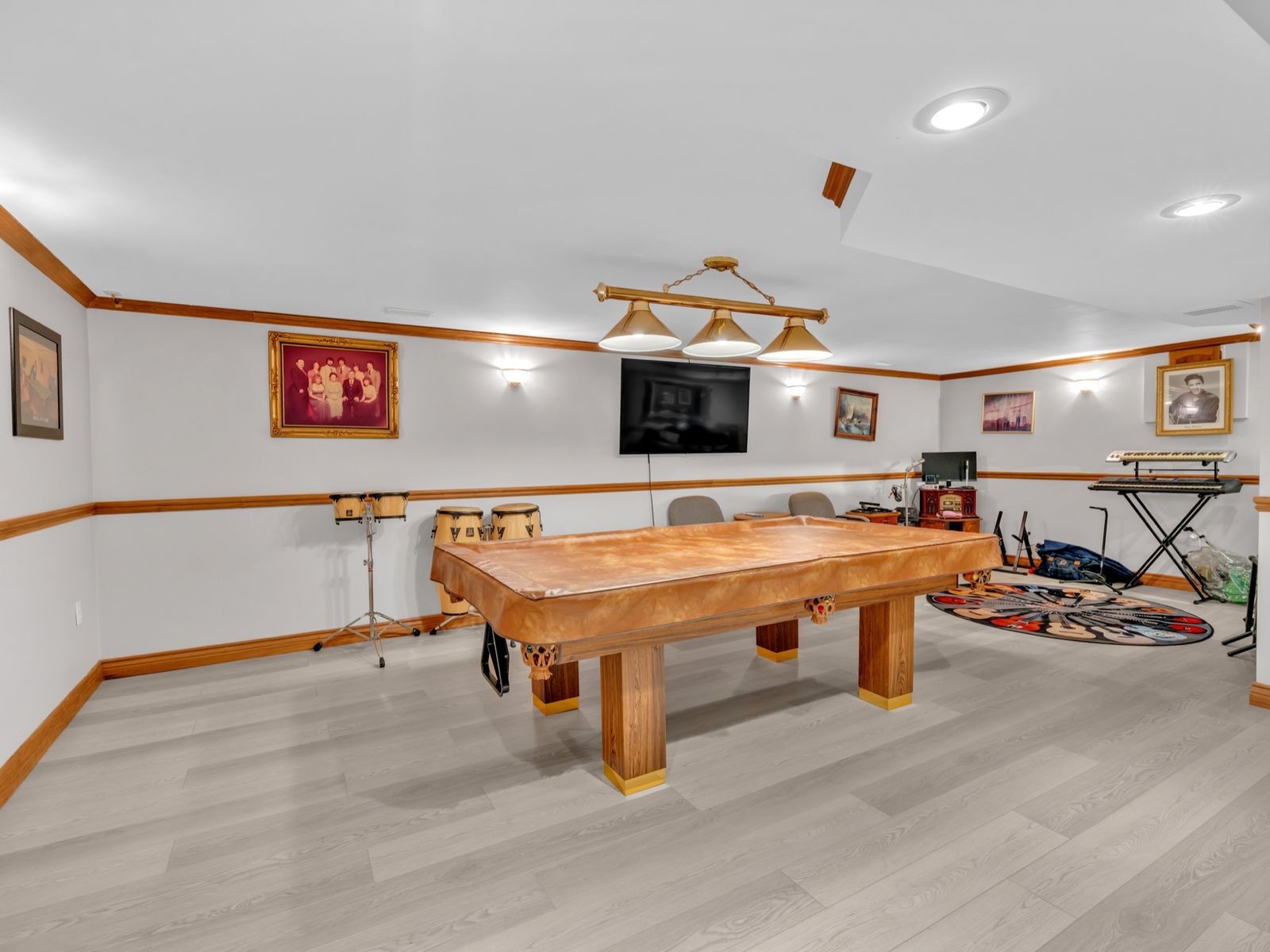 The lower-level recreation room with a pool table and wall-mounted TV.