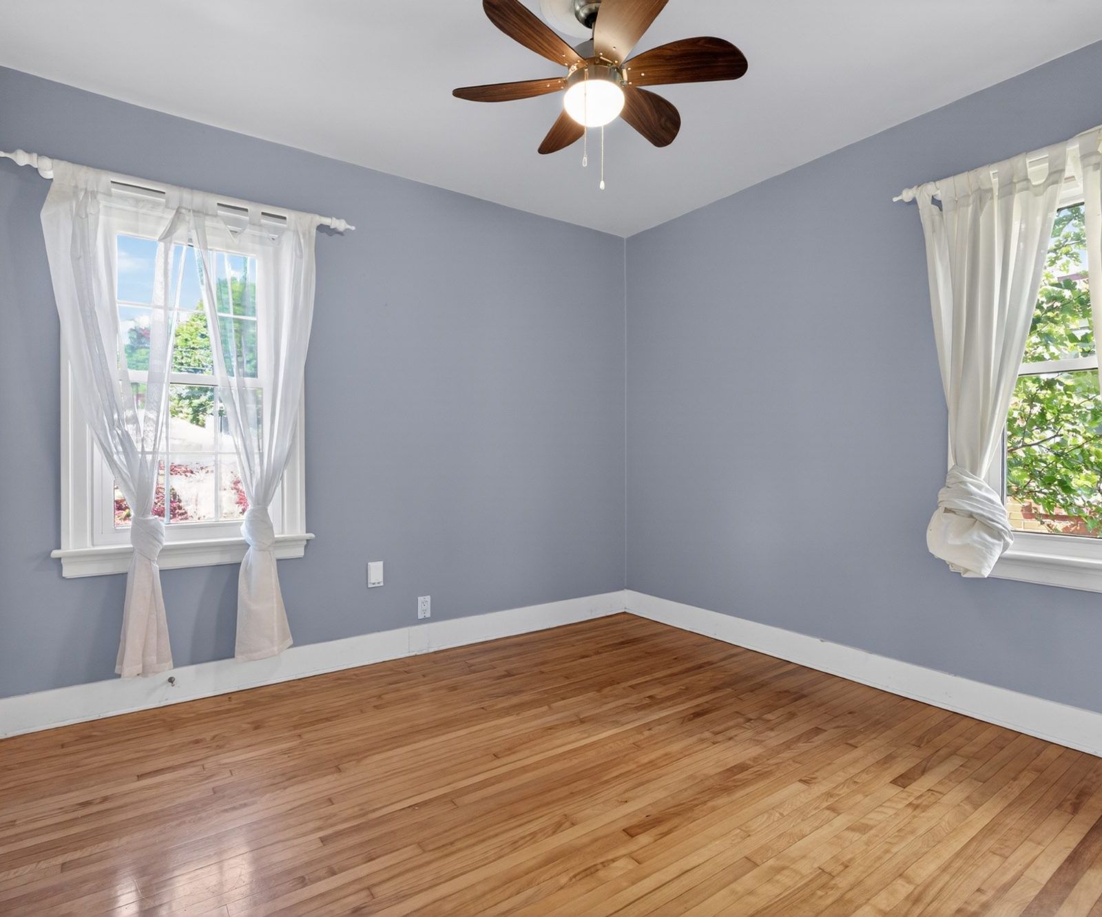 Bright bedroom with two windows and sheer curtains