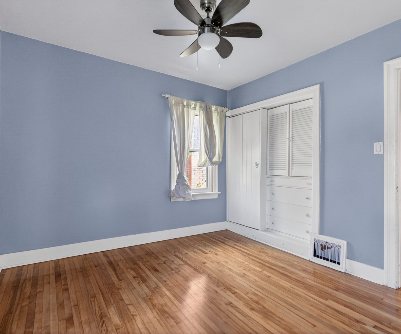 Bedroom with built-in white closet with drawers and ceiling fan