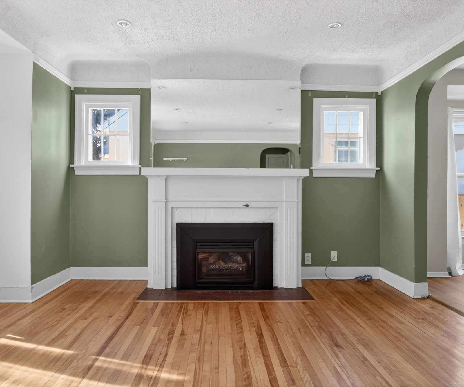 White-mantel gas fireplace flanked by two windows, living room