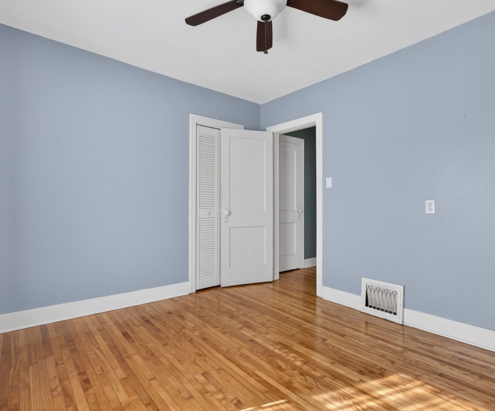 Bedroom with louvre closet doors and hardwood floor