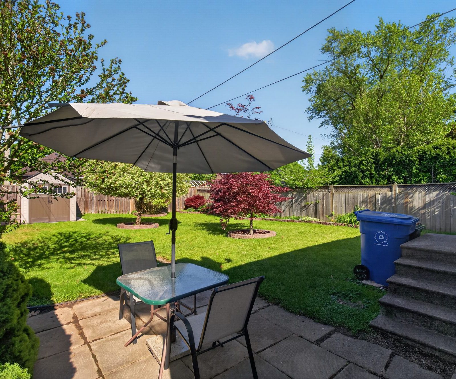 Backyard patio with table, chairs, and umbrella
