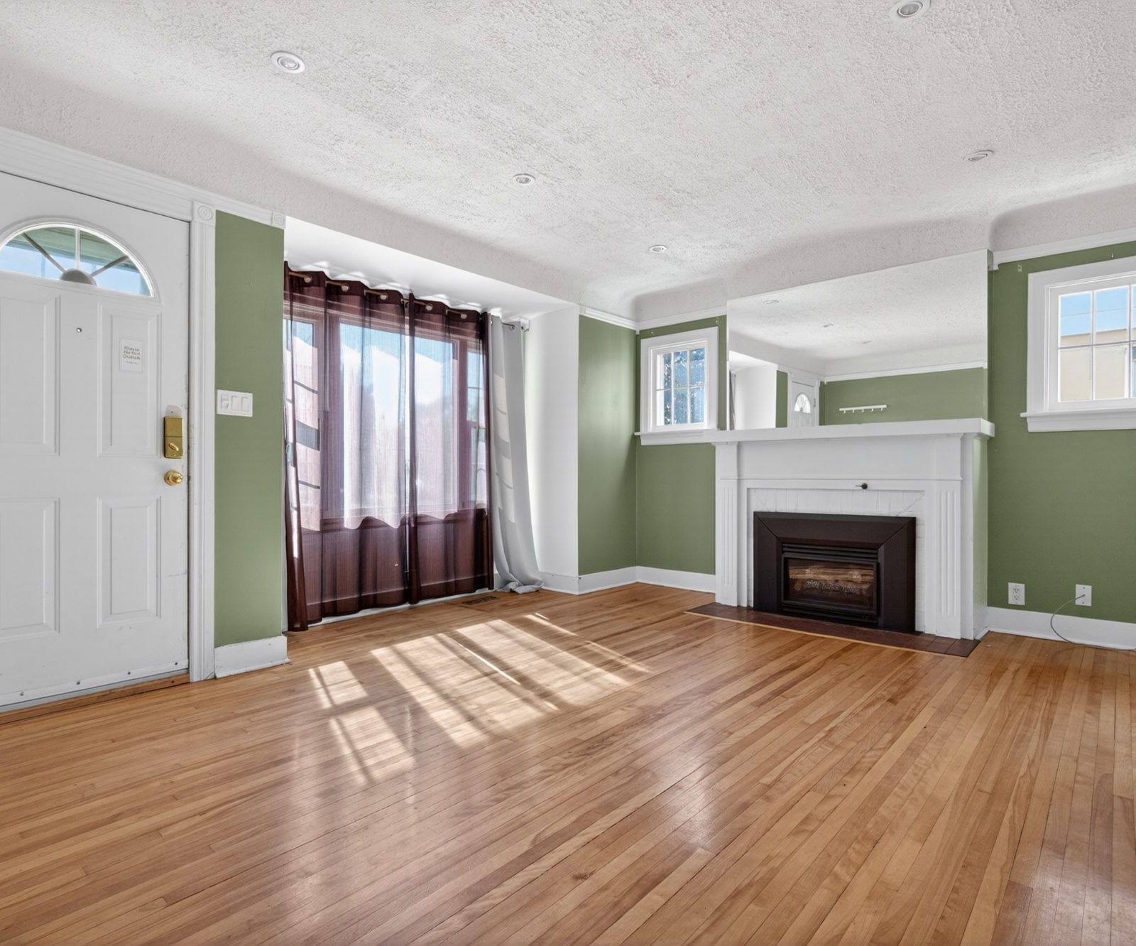 Living room with hardwood floors, green walls, and gas fireplace