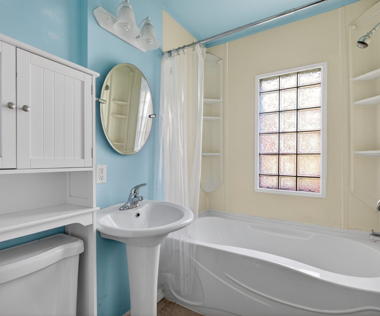 Bathroom with pedestal sink, bathtub, glass block window