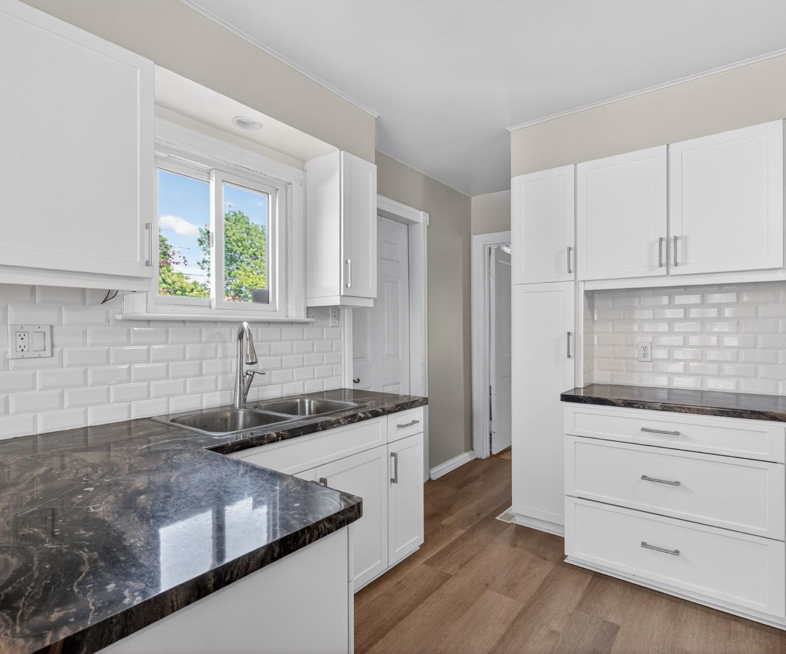 Updated kitchen with white cabinets, black marble countertops, subway tile backsplash