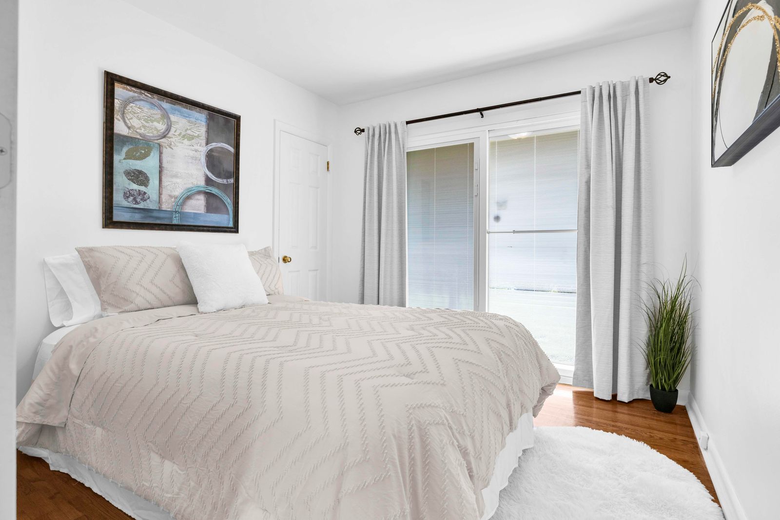 Primary bedroom with a beige bed, white walls, sliding glass door, and flooring.