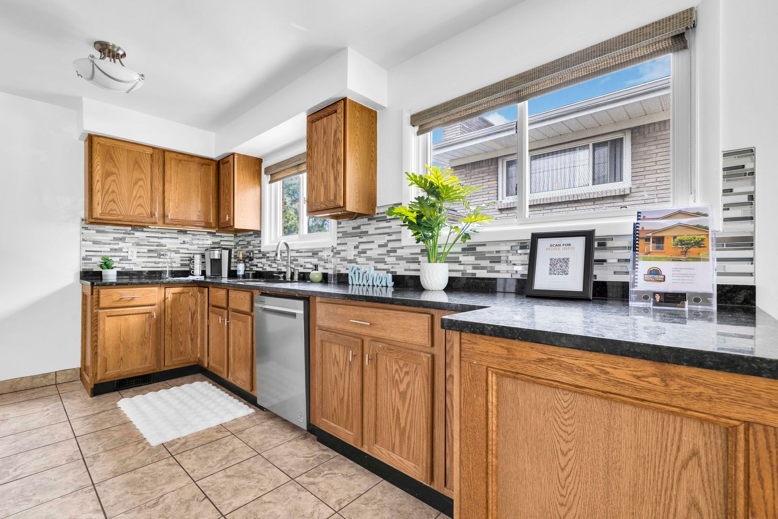 Kitchen with wooden cabinetry, black countertops, tiled backsplash, and appliances.