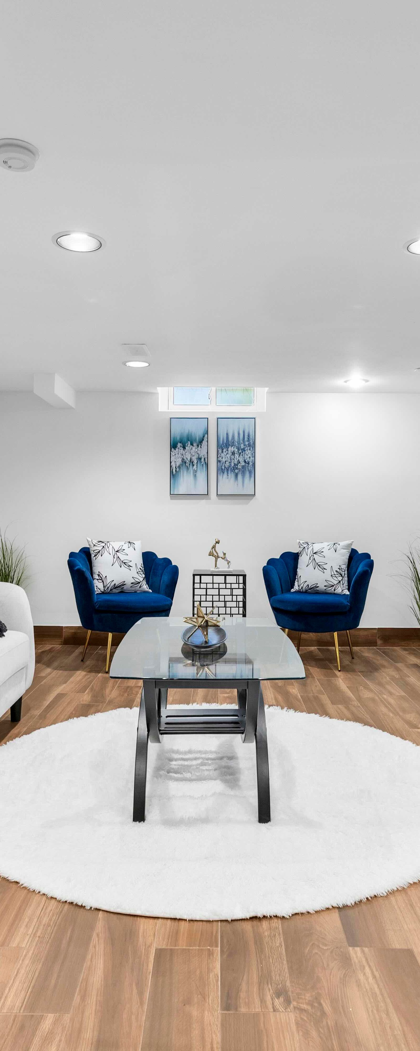 Basement living area featuring seating, a TV console, artwork, and wood-look flooring.