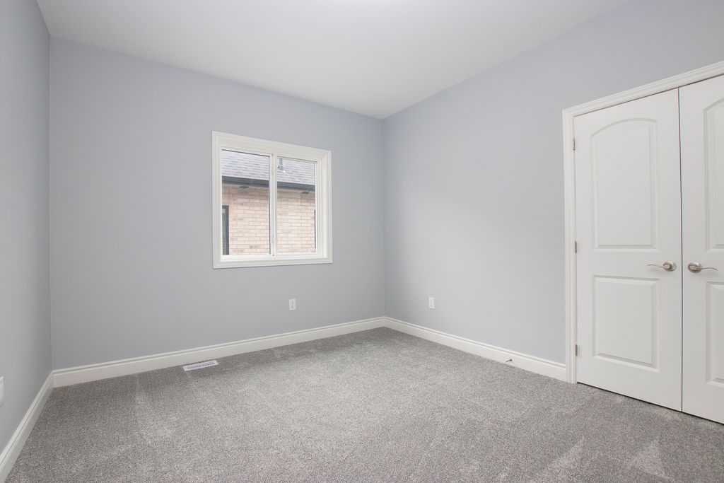 Carpeted bedroom with window and double white closet doors