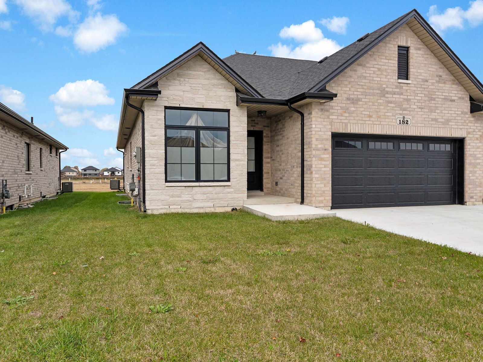 Wide front elevation showing driveway, lawn, and side yard