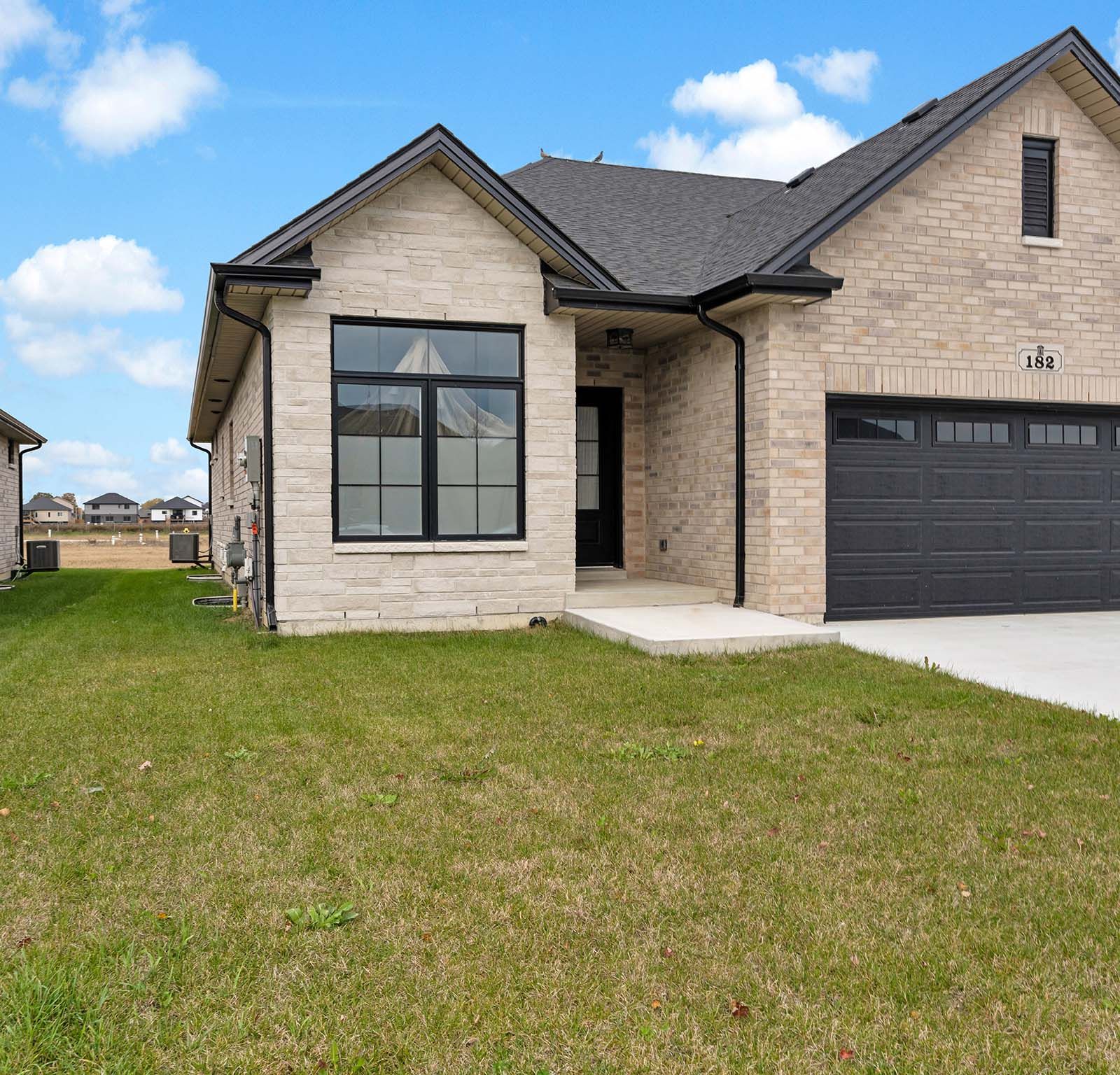 Wide front elevation showing driveway, lawn, and side yard