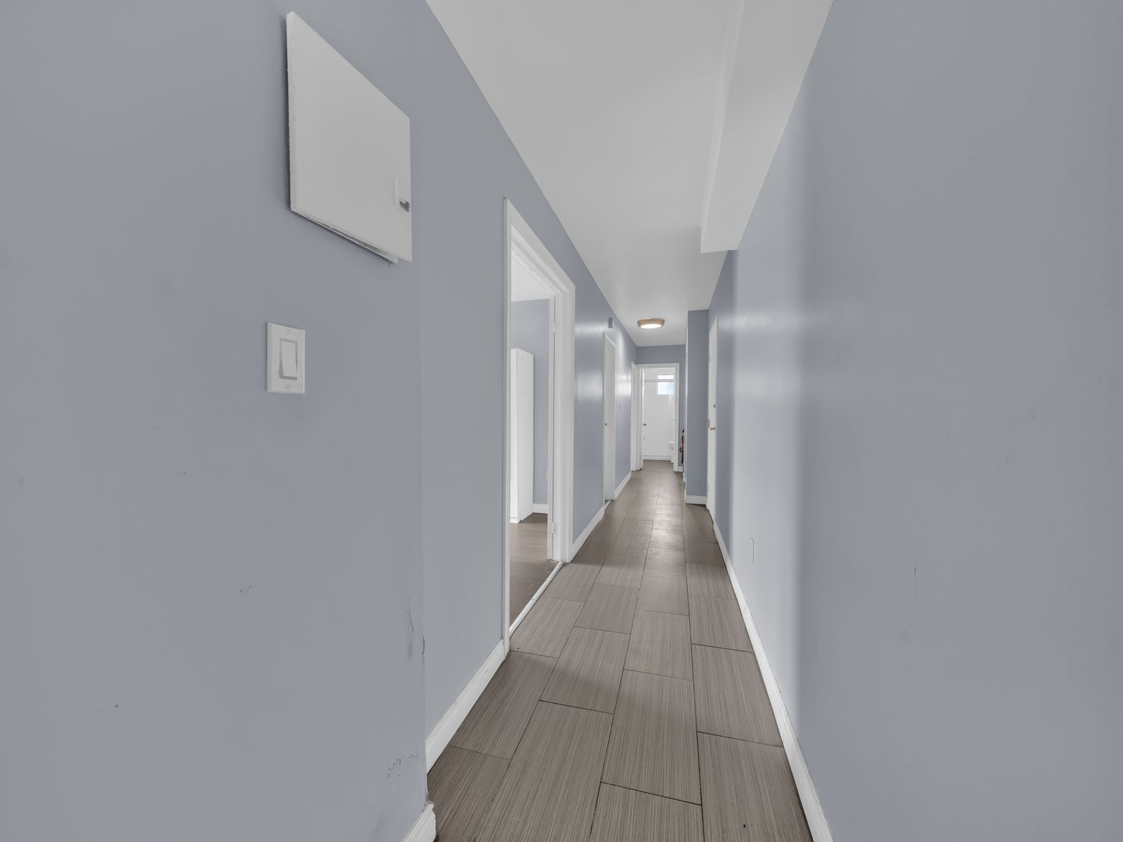 Long hallway with blue walls and tile floor