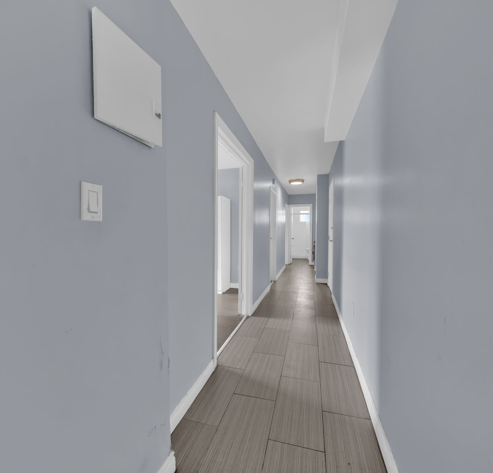 Long hallway with blue walls and tile floor