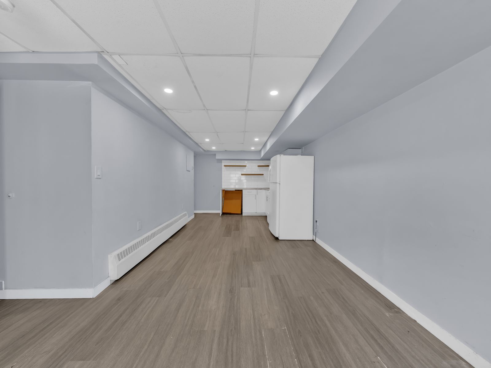 Long living room with grey walls and wood-look flooring
