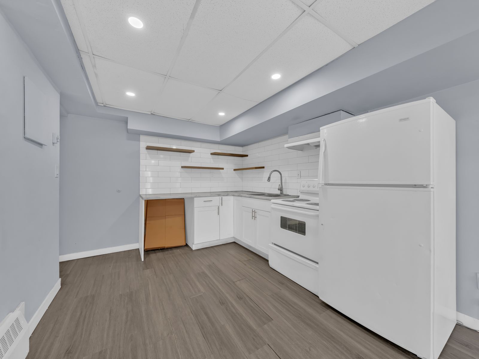 Kitchen with white cabinetry, tile backsplash, and wooden floating shelves