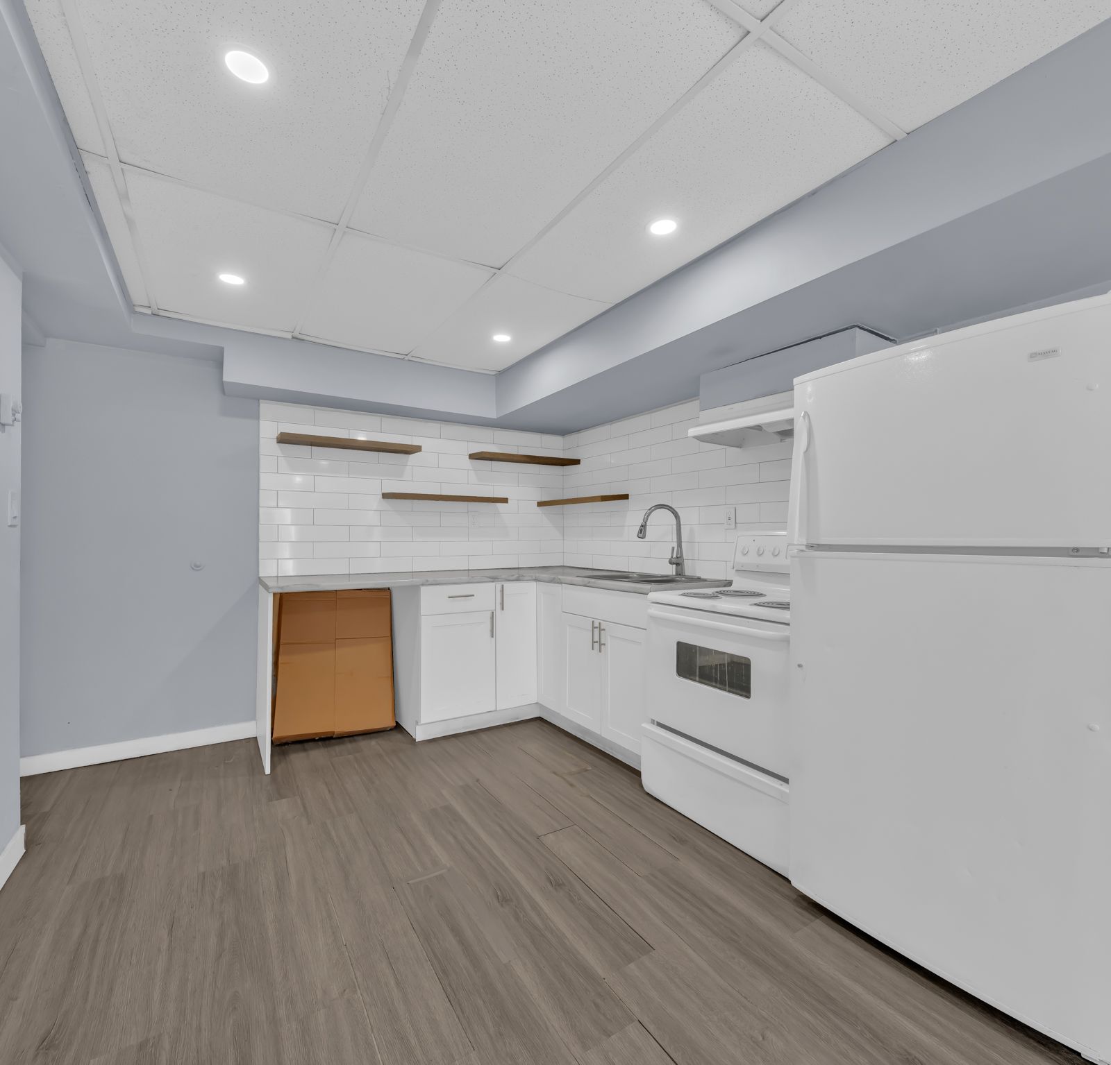 Kitchen with white cabinetry, tile backsplash, and wooden floating shelves