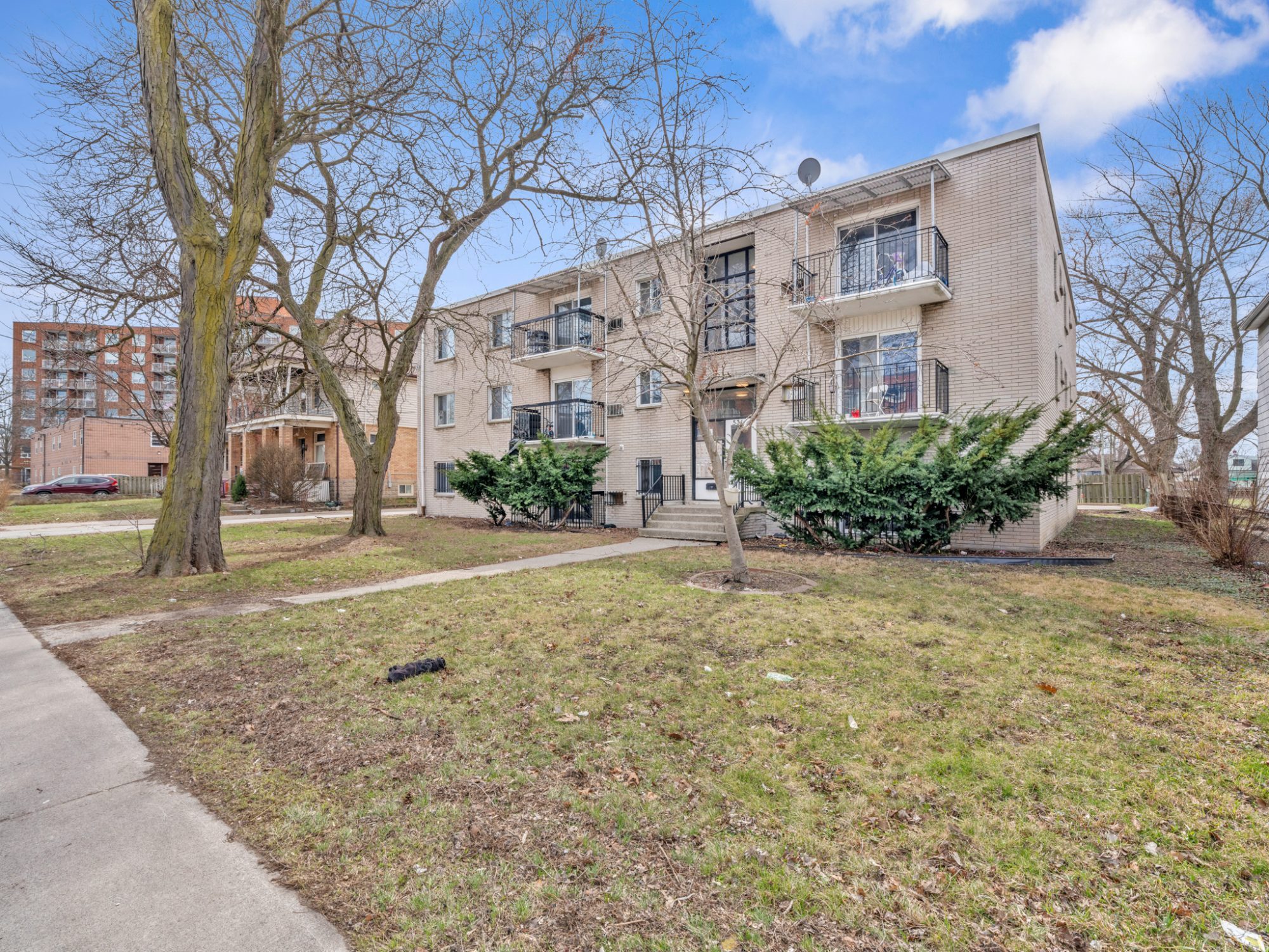 Front exterior of 531 Mill Street - three-storey brick apartment building with balconies and mature tree