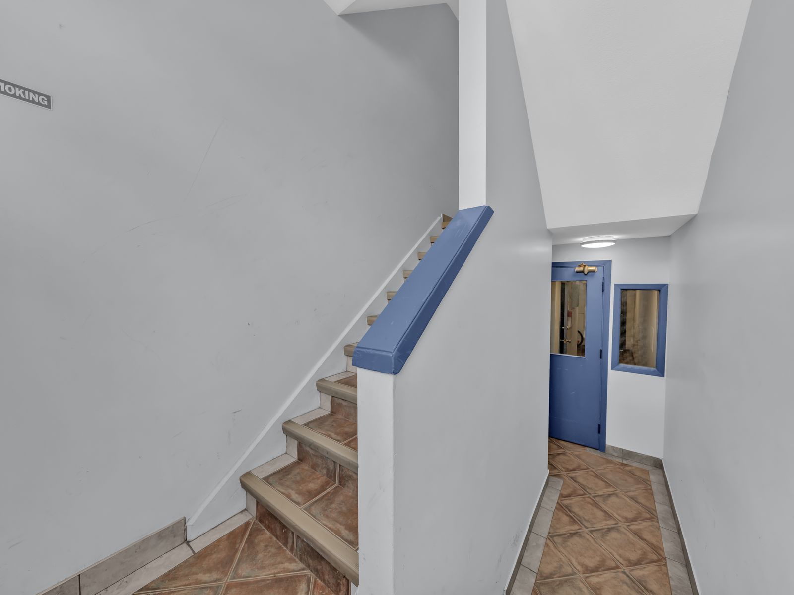 Interior staircase with tile steps and blue handrail
