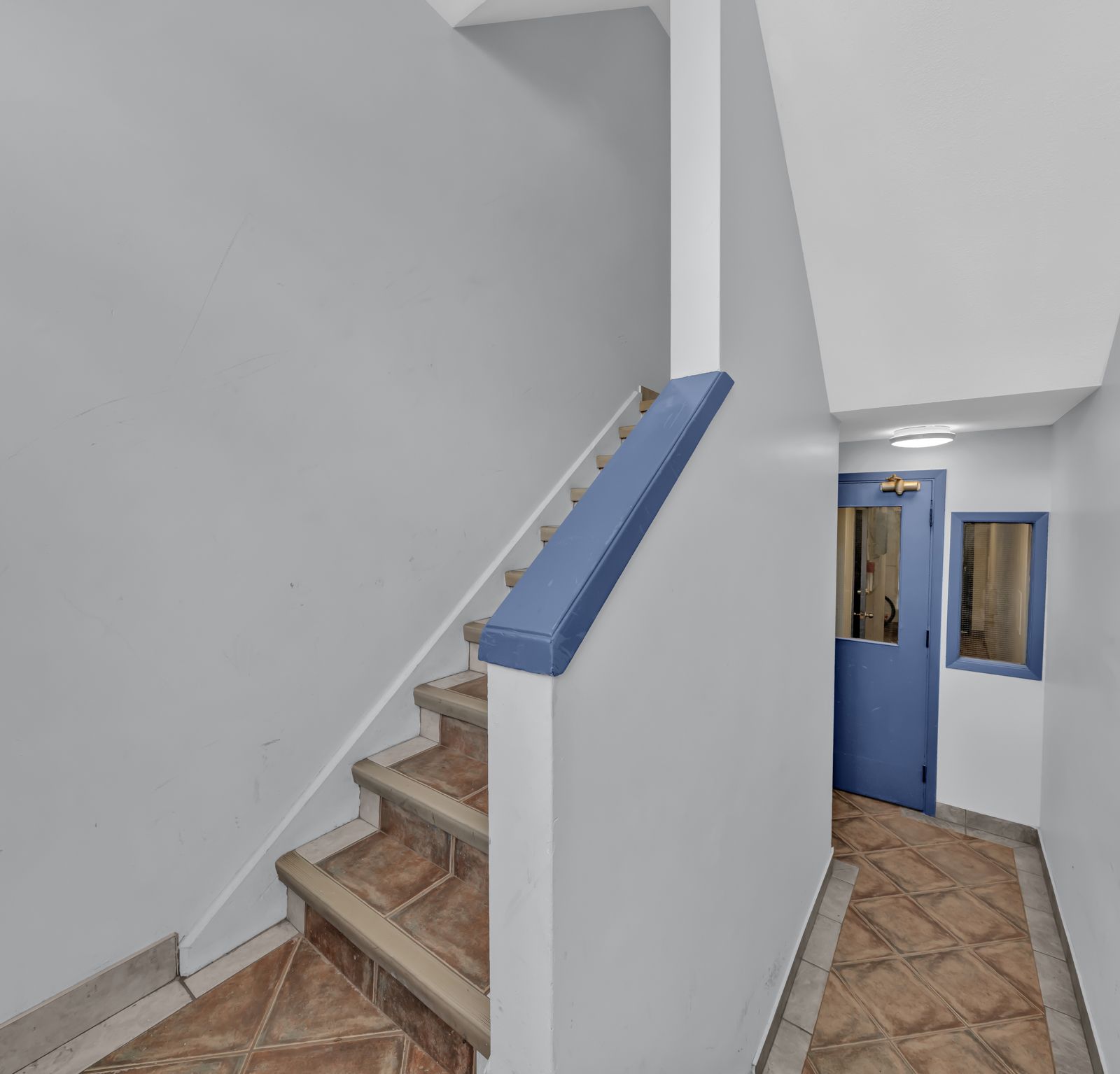 Interior staircase with tile steps and blue handrail