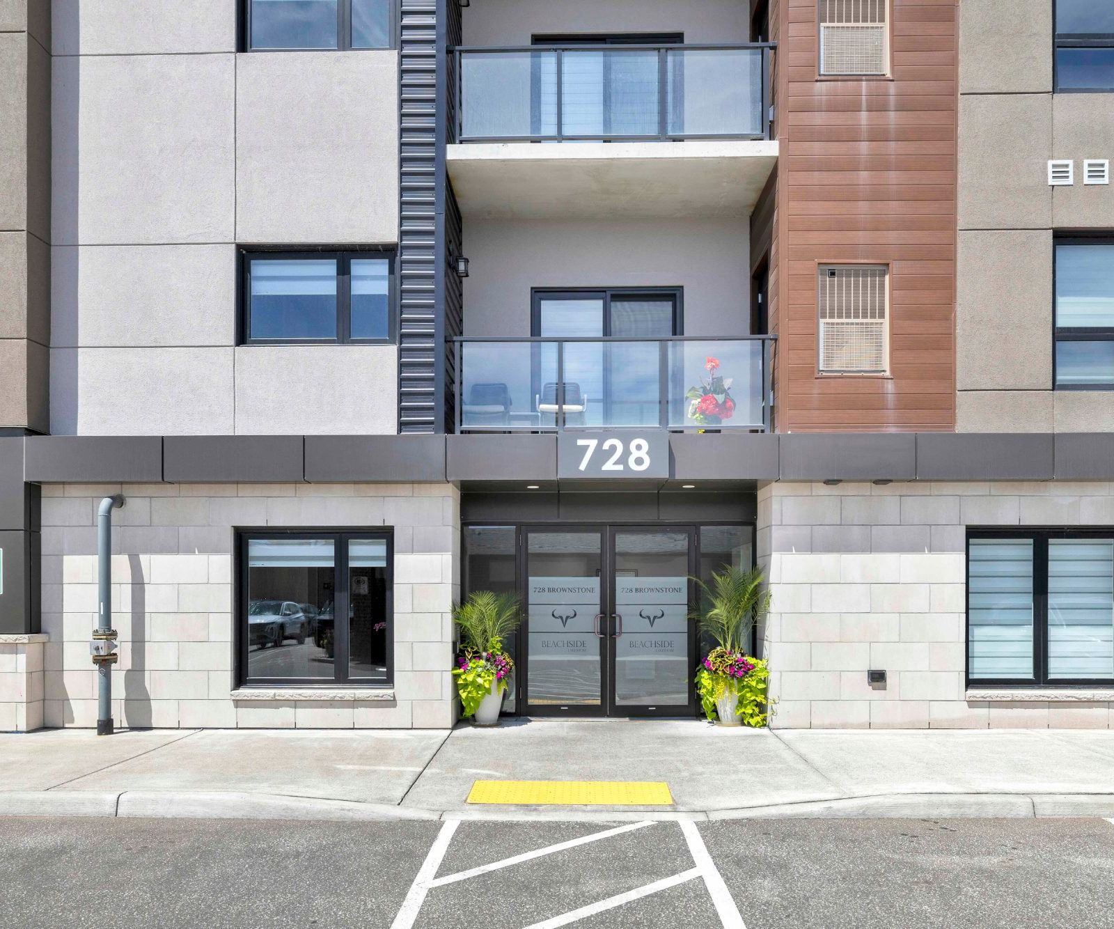 Front entrance of 728 Brownstone with double glass doors and decorative planters