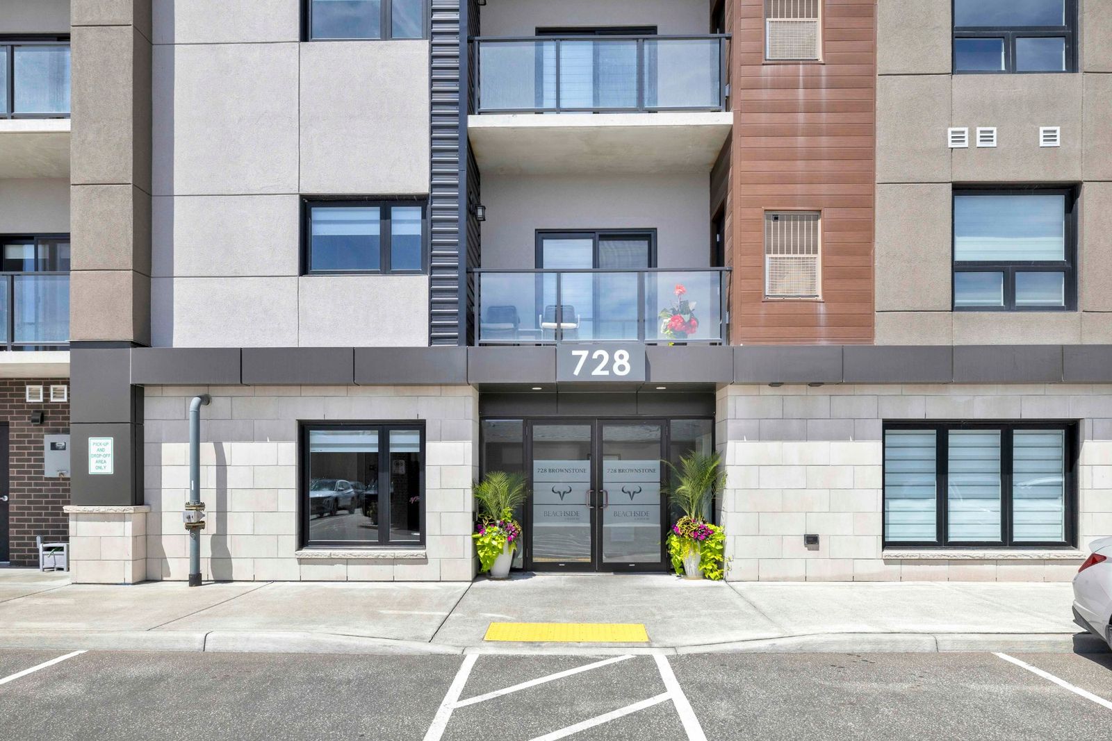Front entrance of 728 Brownstone with double glass doors and decorative planters