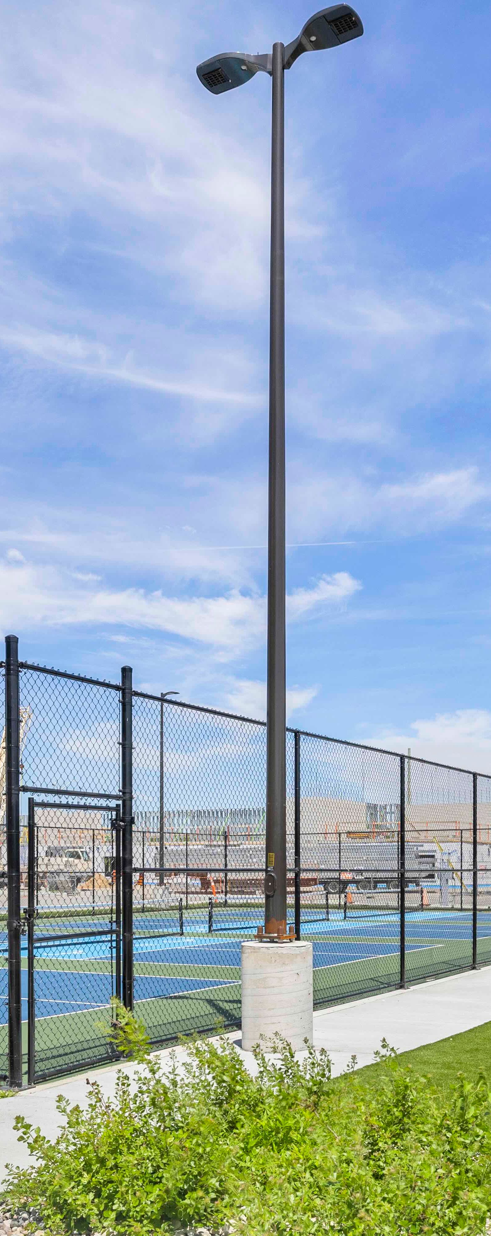Outdoor pickleball courts with chain-link fence and residential building