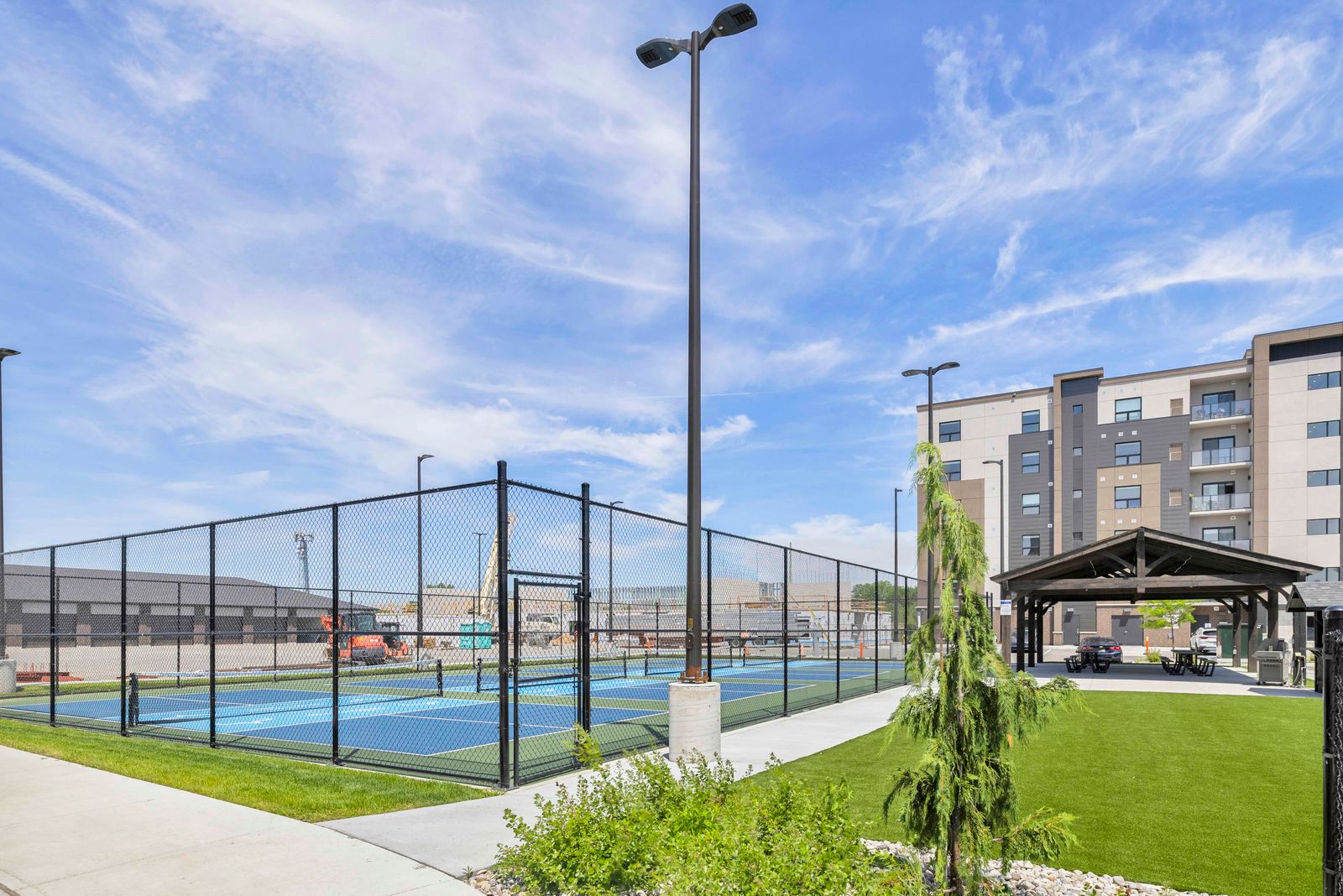 Outdoor pickleball courts with chain-link fence and residential building