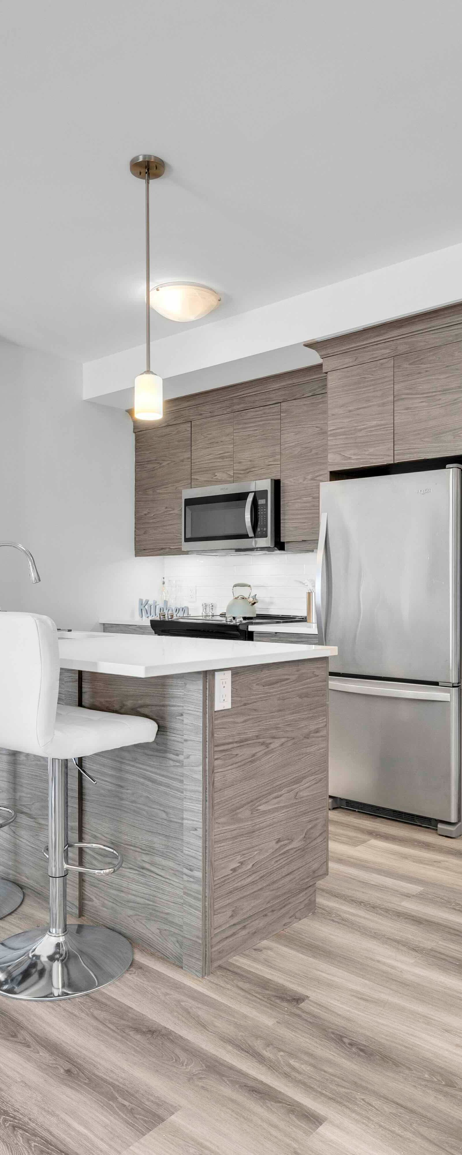 Kitchen island with quartz countertop, bar stools, and pendant lights