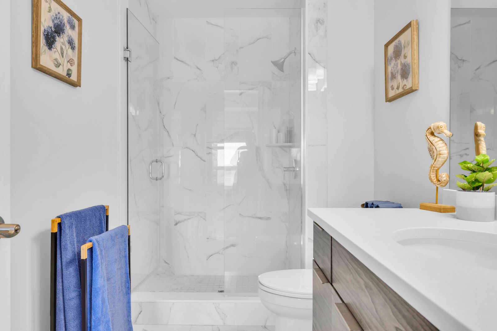 Ensuite bathroom with walk-in glass shower, vanity, toilet, and decorative accents